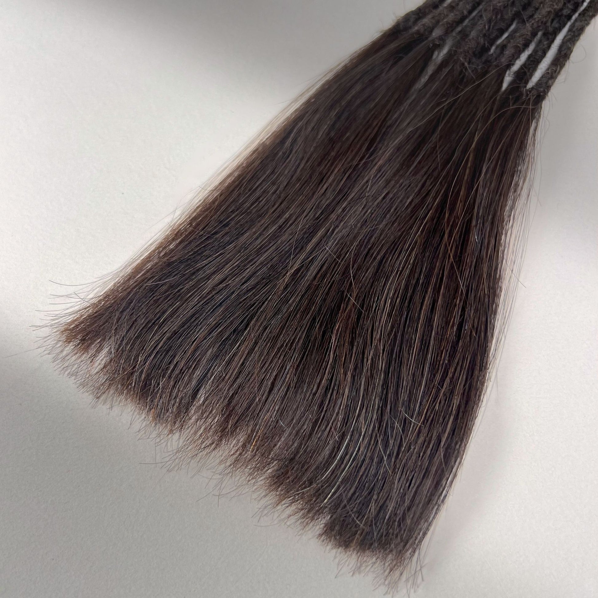 Tip detail of straight loc extensions with long loose ends in Warm Caramel Brown.