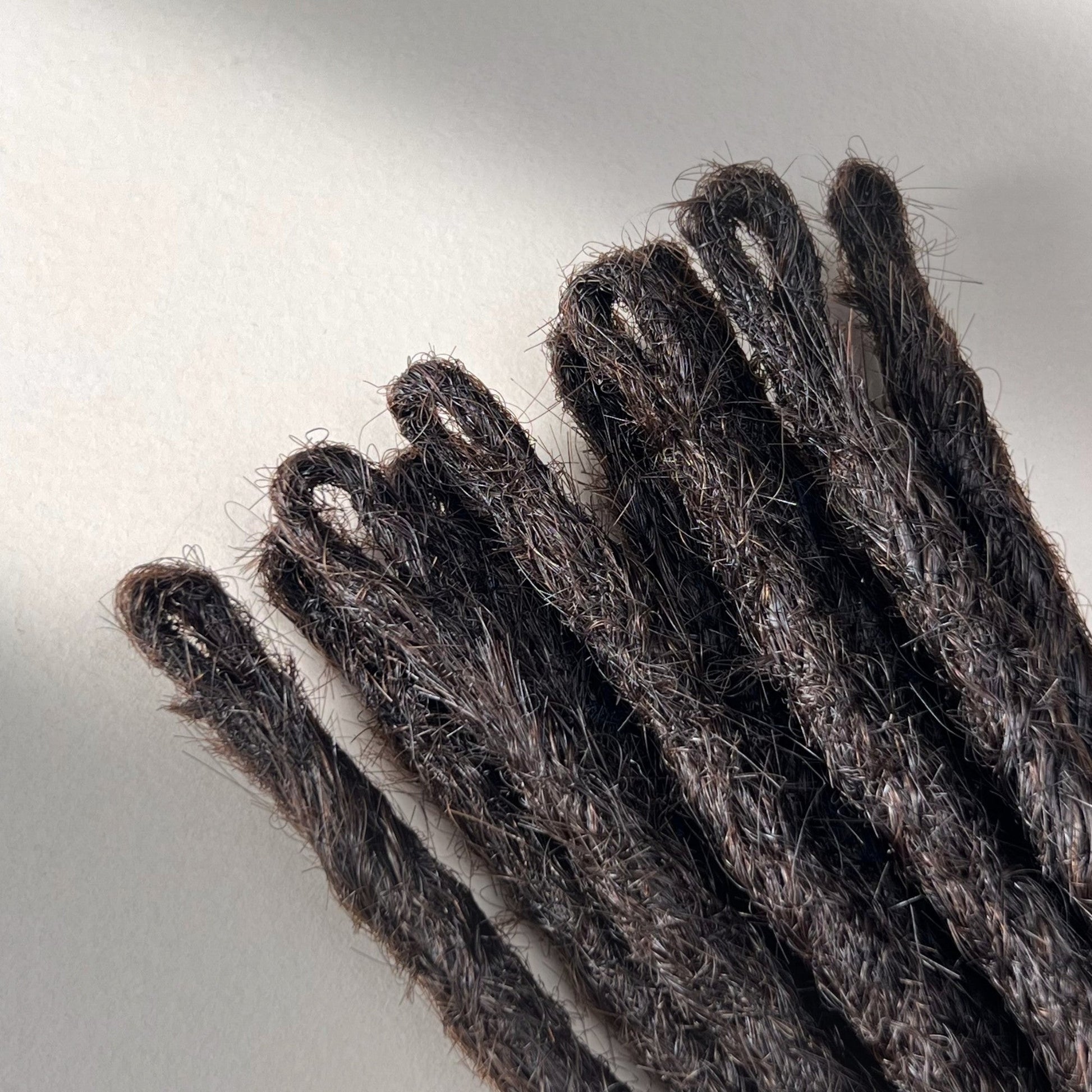 Loop detail of temporary single-ended straight loc extensions with open ends in Deep Brown.