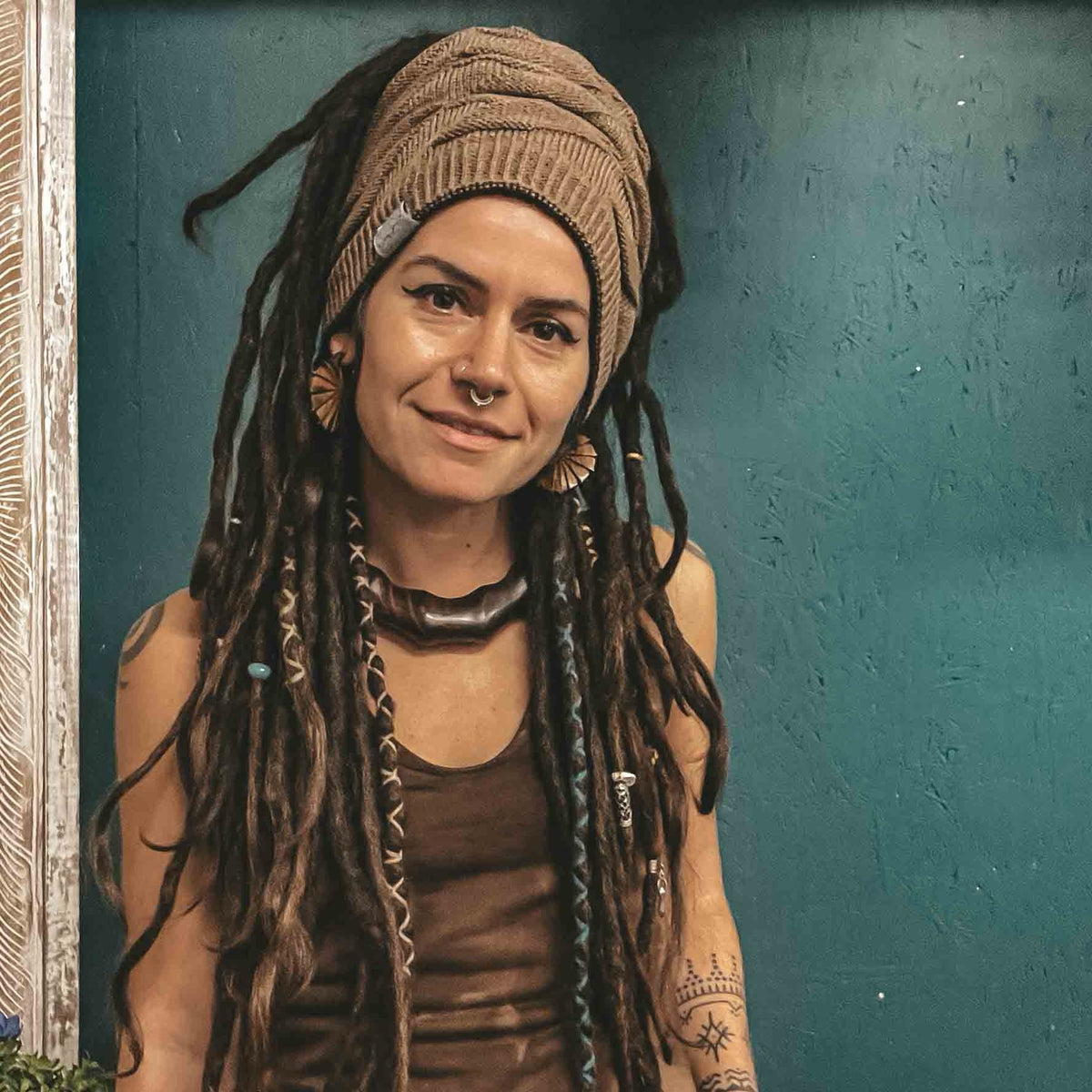 Person with long locs wearing CrafterElena accessories and a knitted beanie