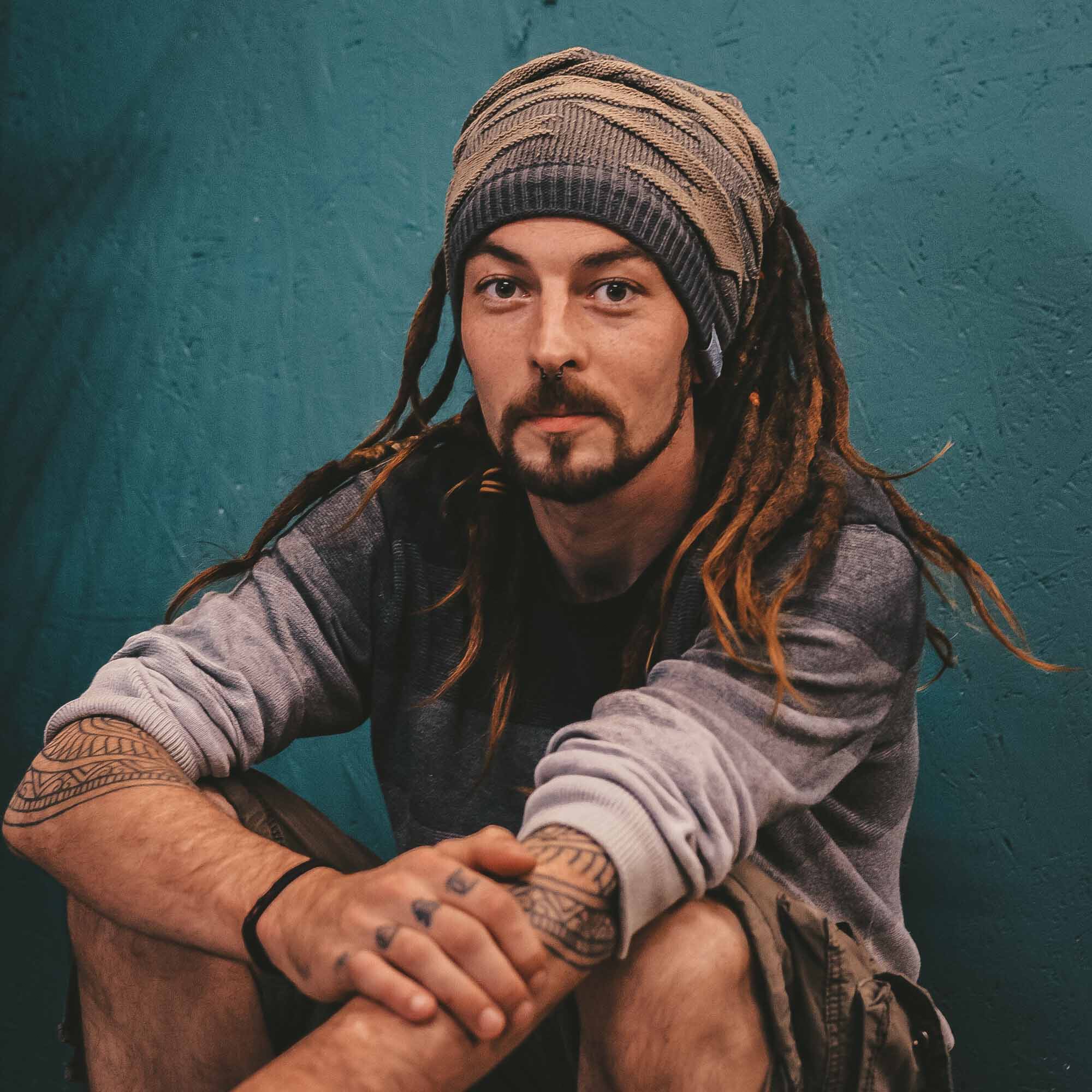 Person wearing a khaki CrafterElena Camo beanie with locs