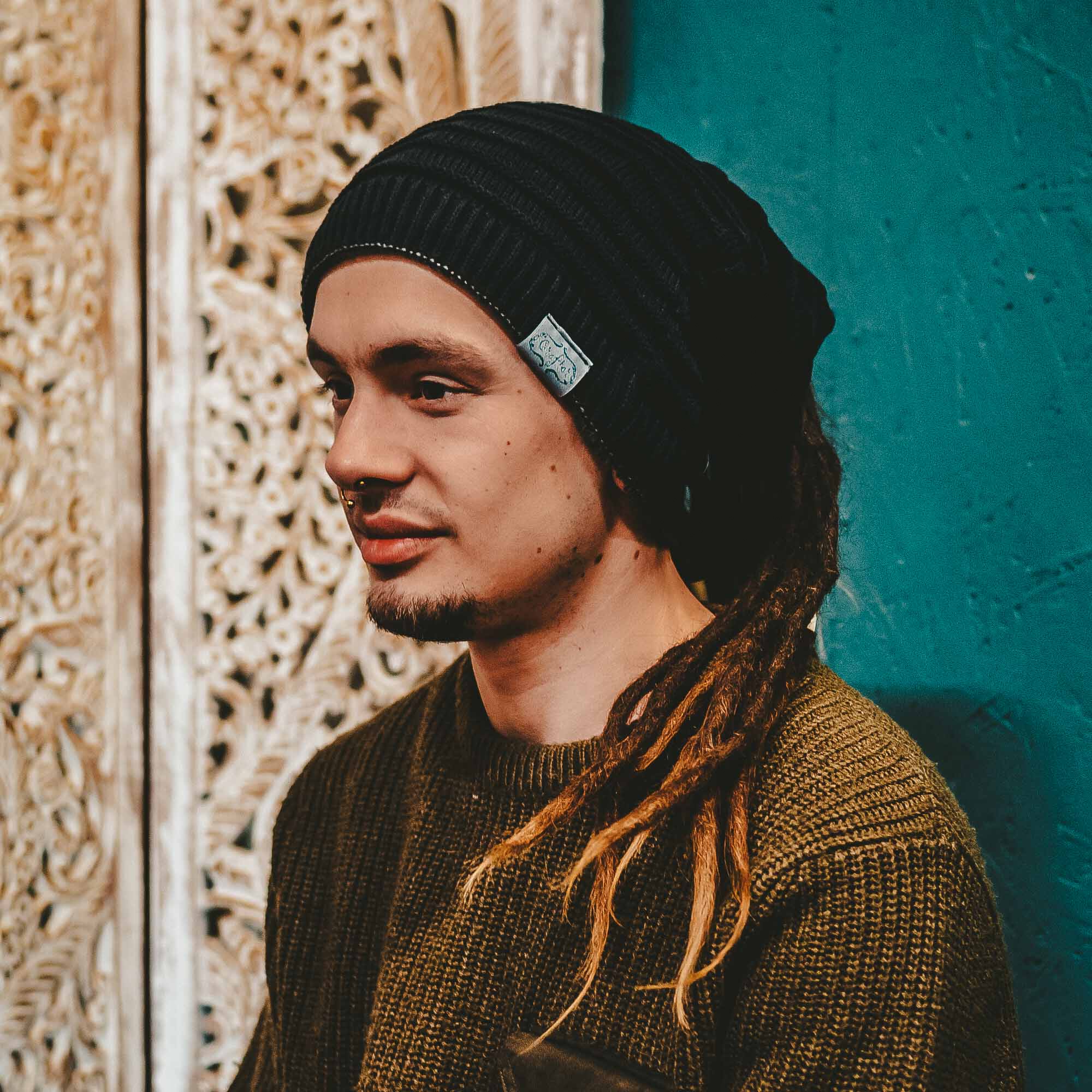 Person wearing a black CrafterElena Simple Stripes beanie with locs