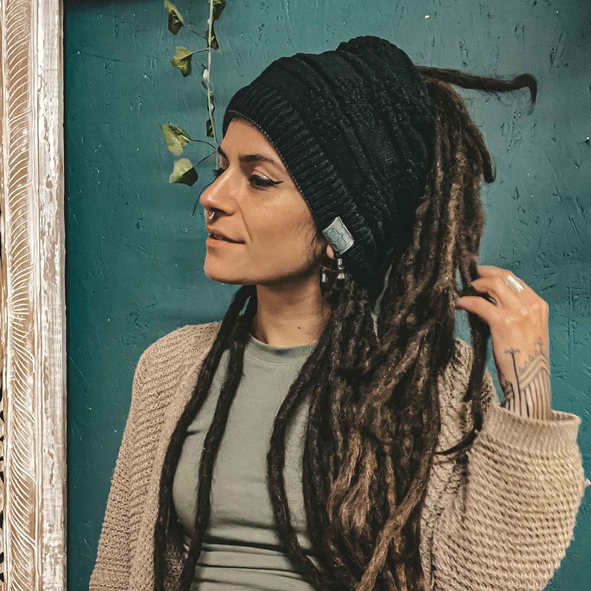 Person wearing a black CrafterElena Squares beanie with long locs