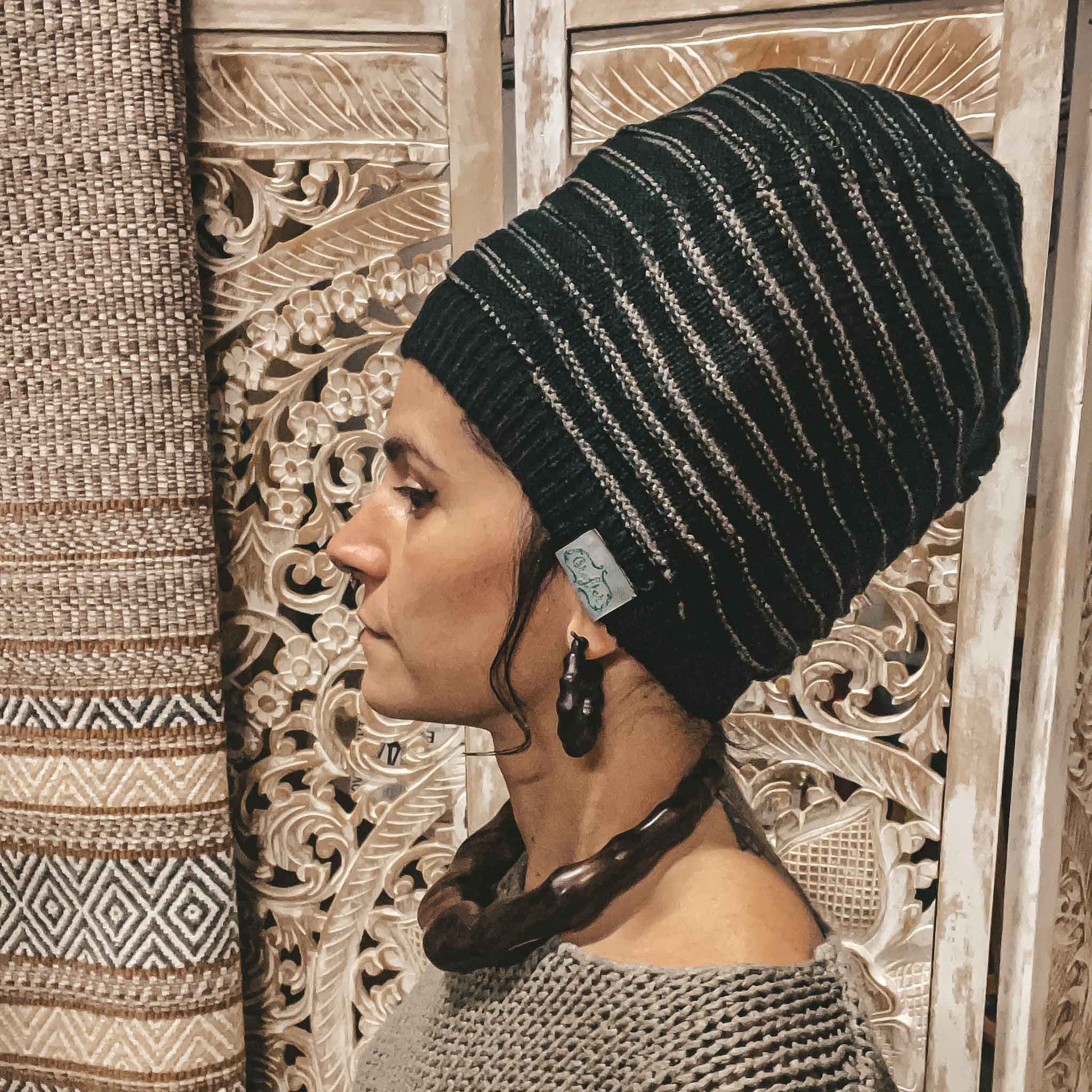 Person wearing a black CrafterElena Striped beanie with locs