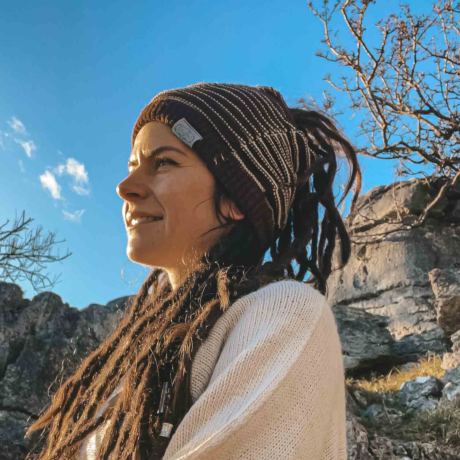 Person wearing a dark brown CrafterElena Striped beanie with locs