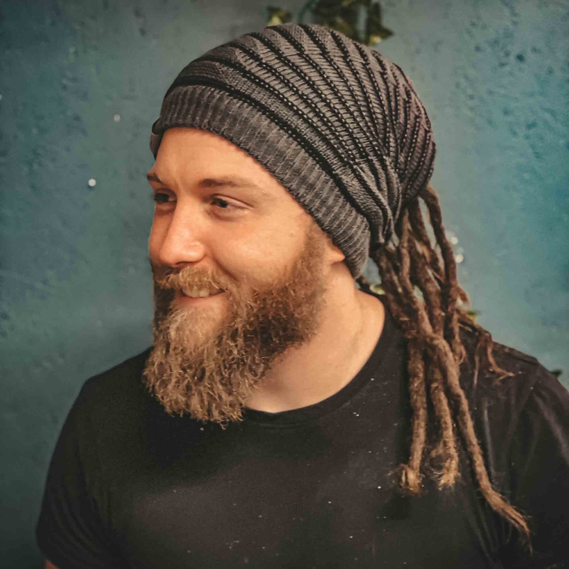Person wearing a grey CrafterElena Striped beanie with locs