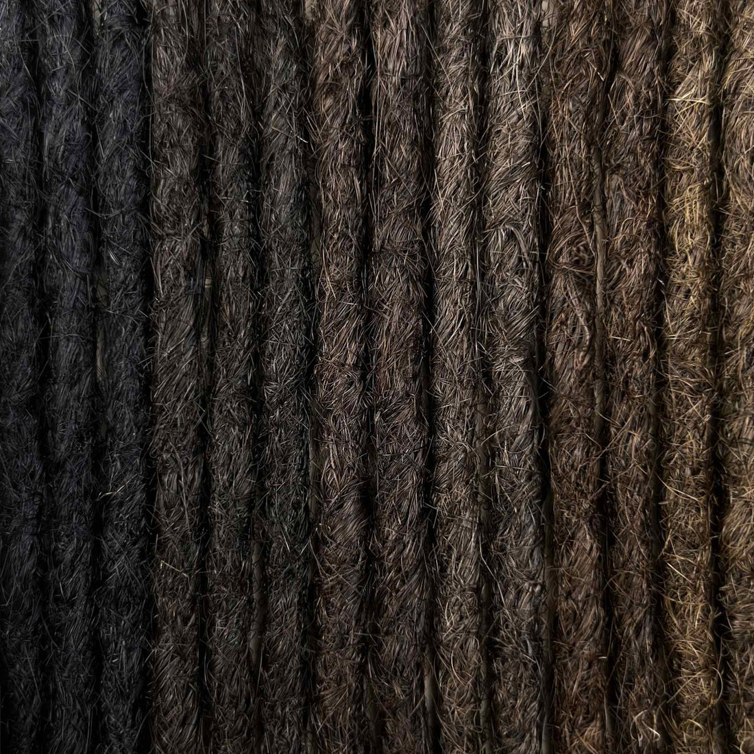 Handcrafted human hair Loc Extensions in the Dark Color Family featuring deep black and dark brown shades.