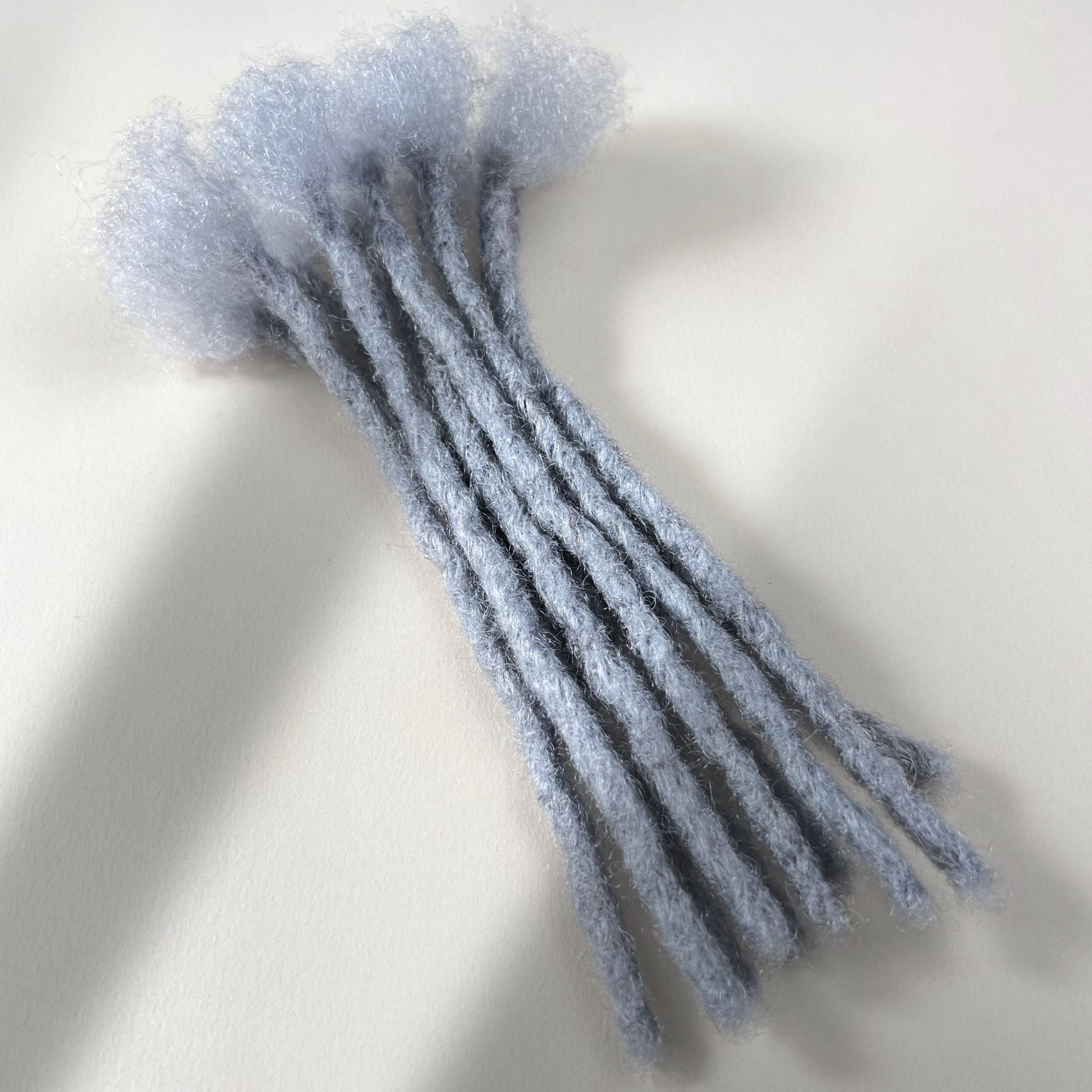 Grey kinky human hair blunt end loc extensions made using the crochet method.