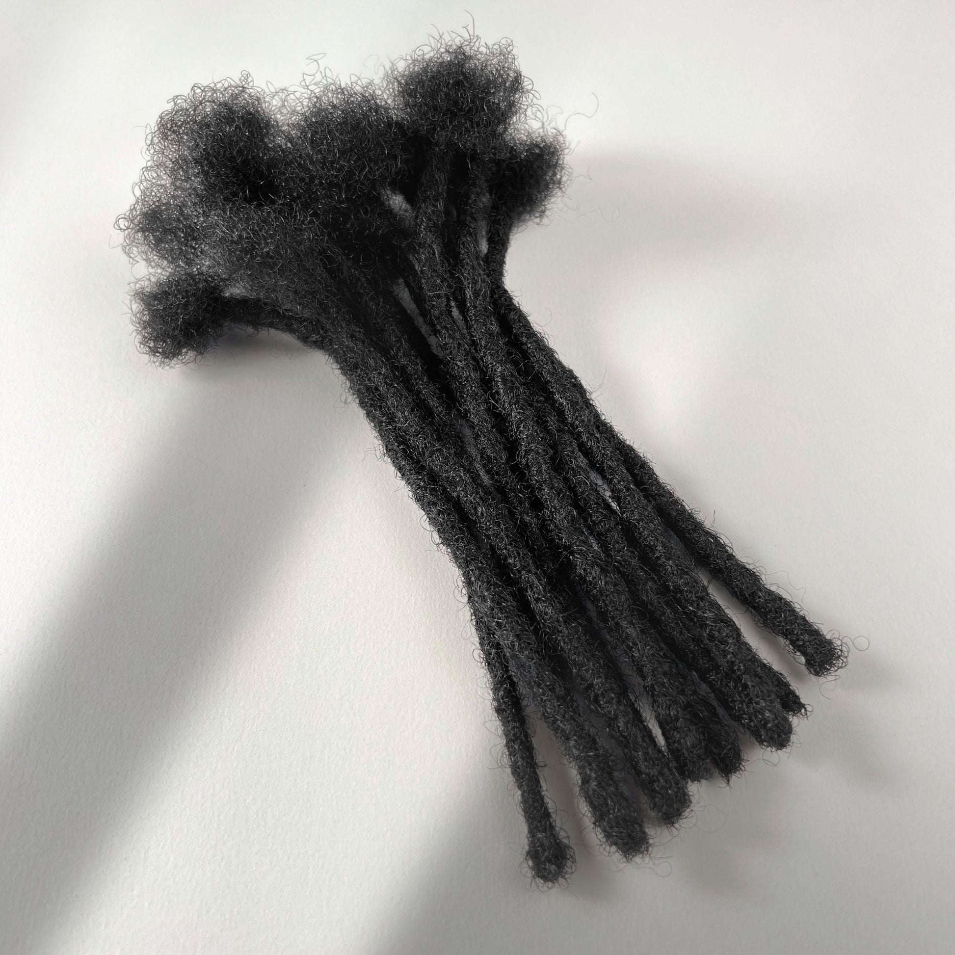 Natural Black kinky human hair blunt end loc extensions made using the crochet method.