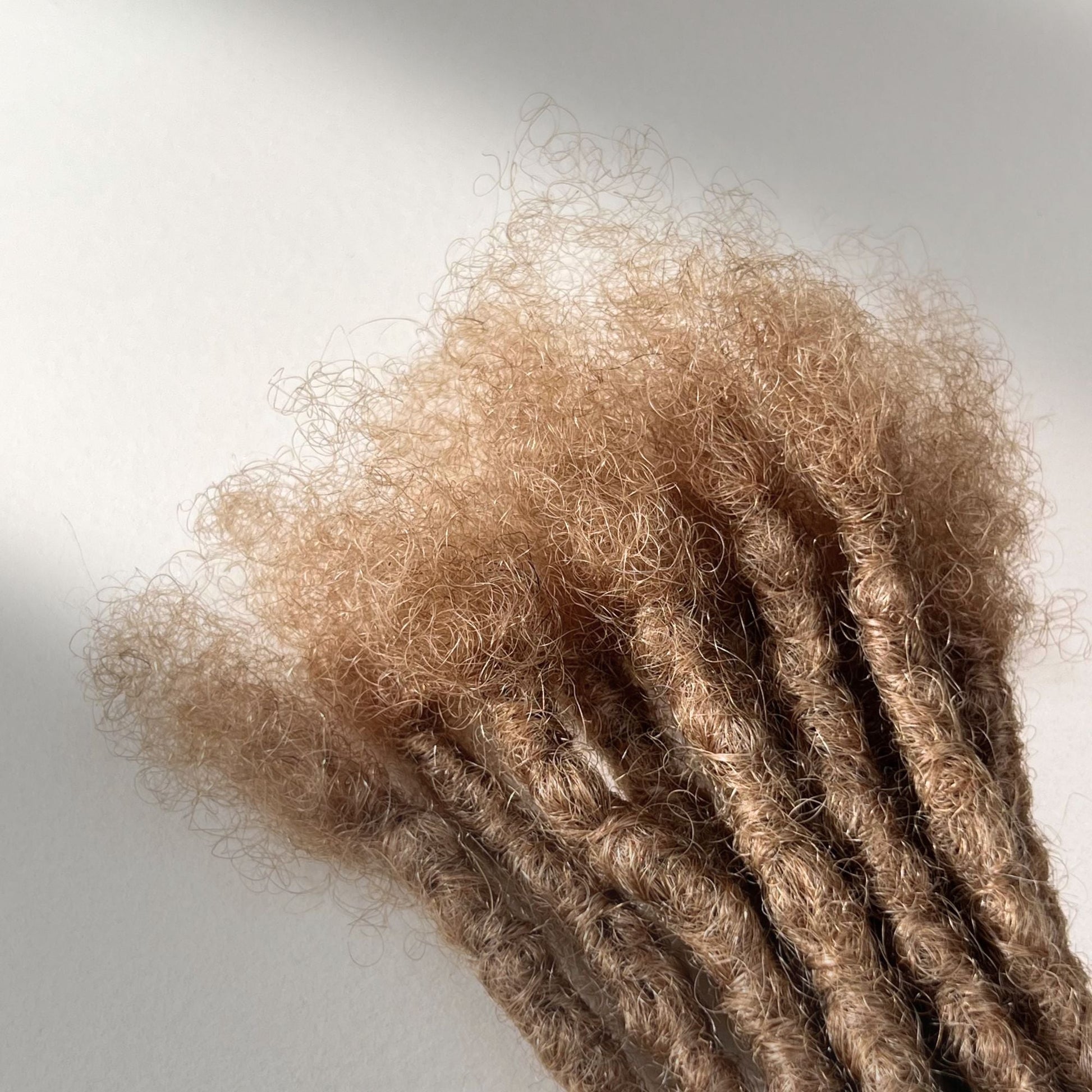 Close-up of the connection point on Dark Blonde kinky human hair loc extensions.