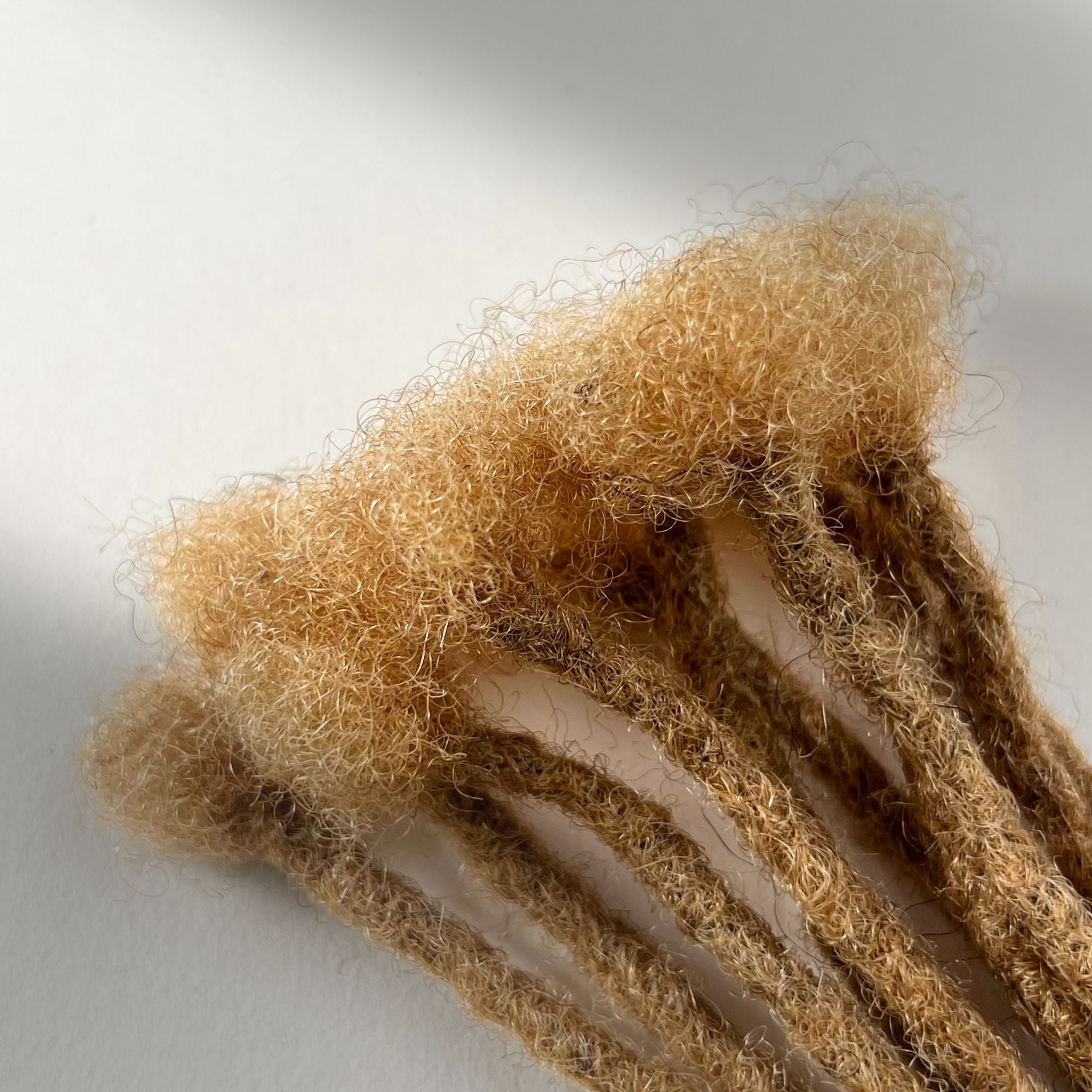 Close-up of the connection point on Honey Blonde kinky human hair loc extensions.