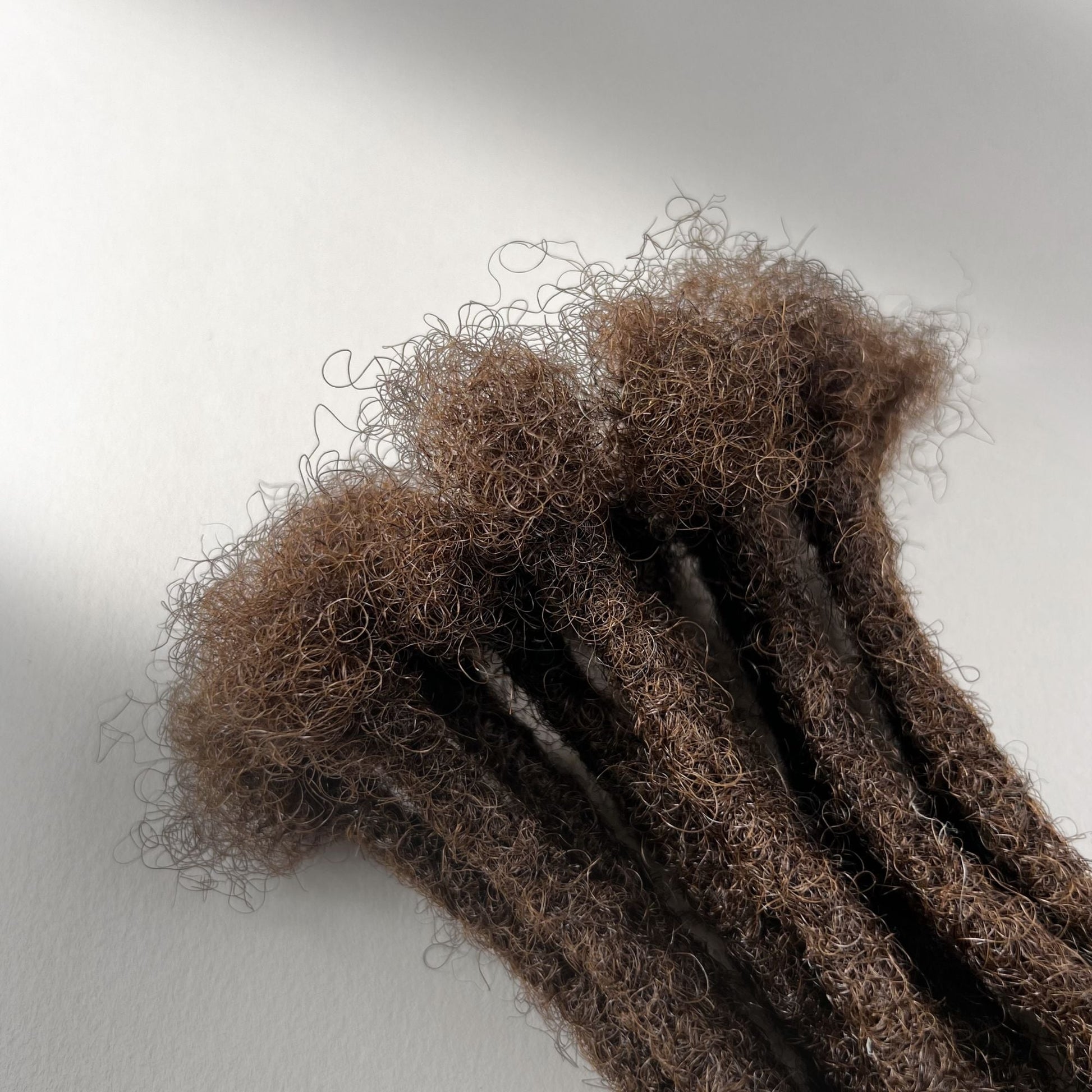 Close-up of the connection point on Medium Brown kinky human hair loc extensions.