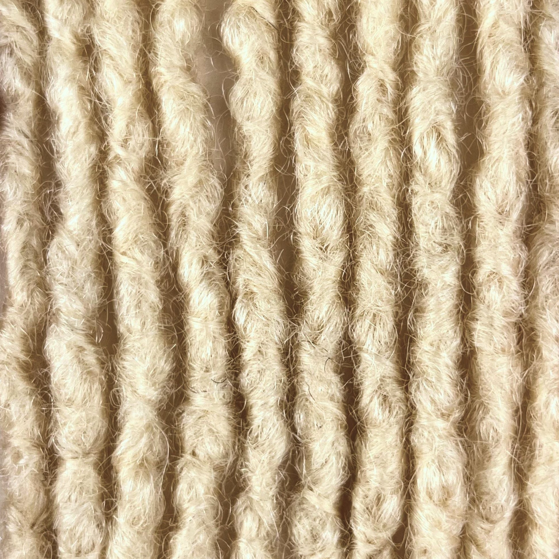 Close-up of Bleach Blonde kinky human hair loc extensions made using the interlocking method.