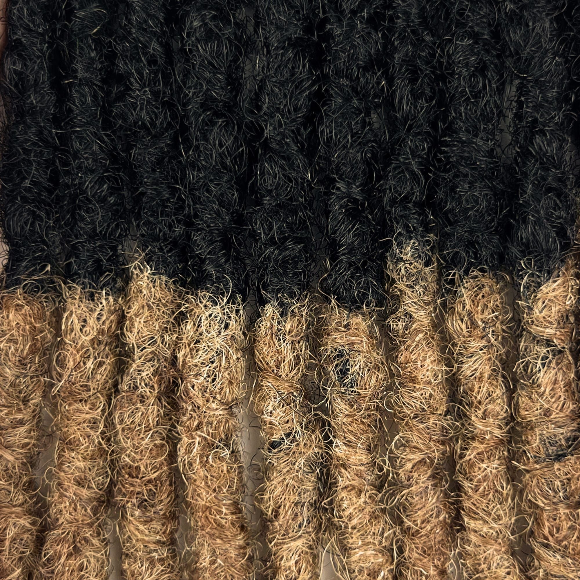 Close-up of Honey Blonde Ombre kinky human hair loc extensions made using the interlocking method.