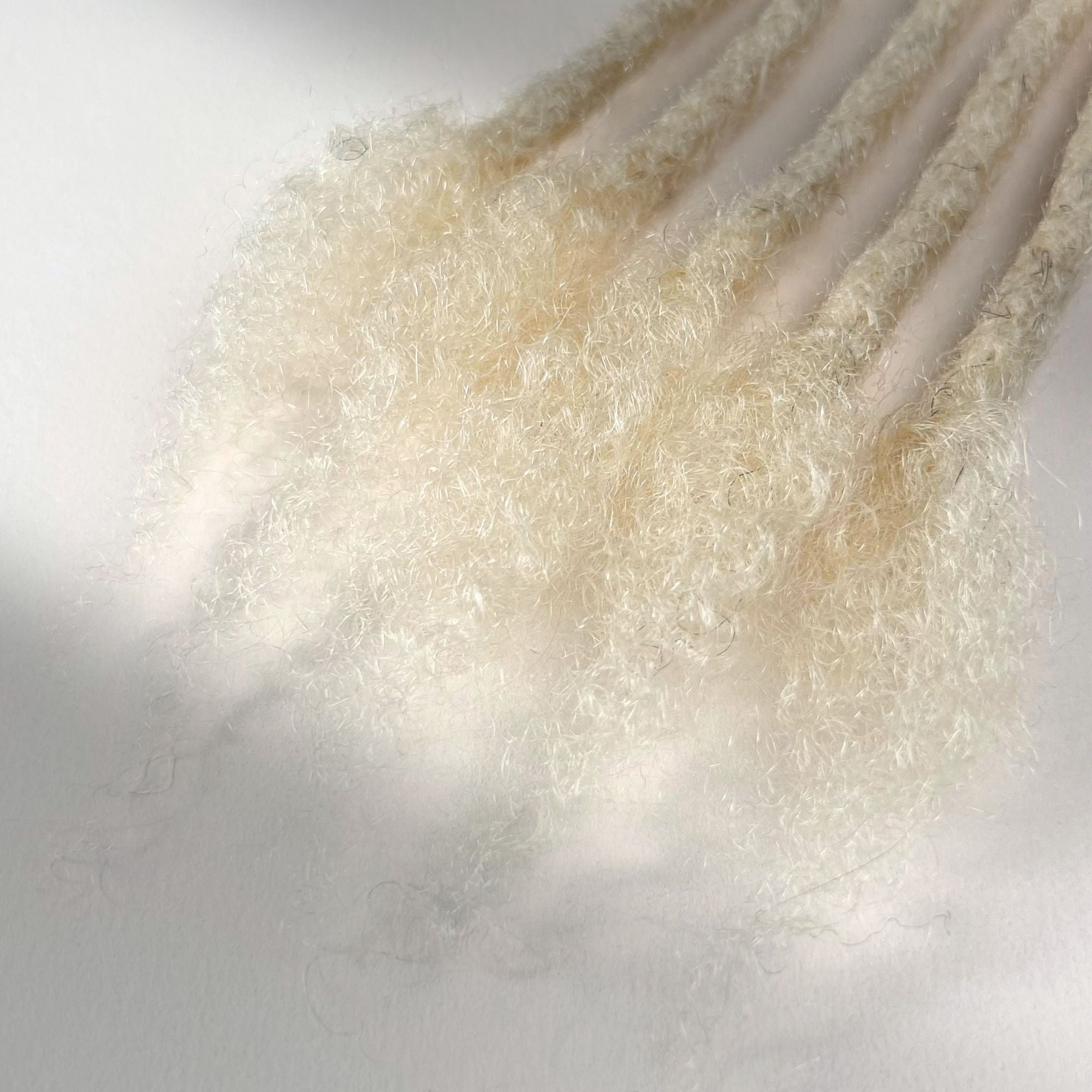 Close-up of the open ends on Bleach Blonde kinky human hair loc extensions.