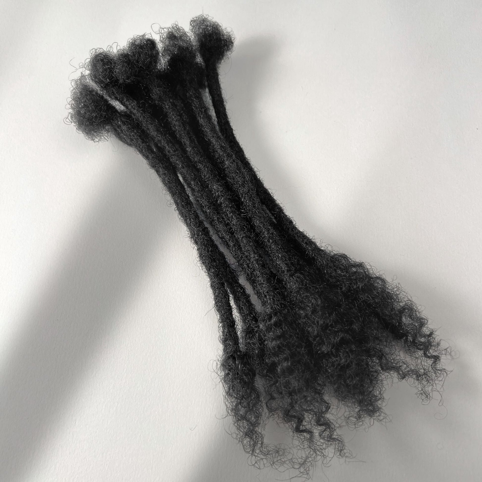 Natural Black kinky human hair open end loc extensions made using the crochet method.