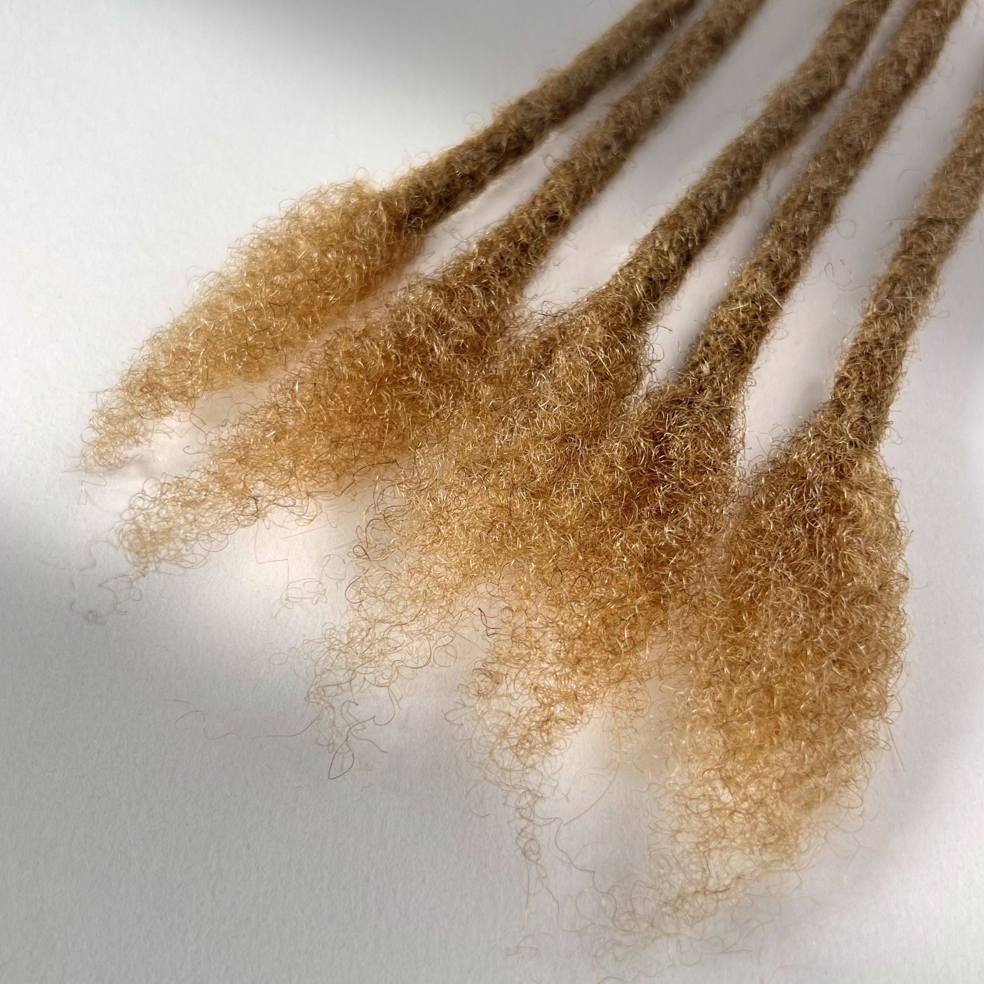 Close-up of the open ends on Honey Blonde kinky human hair loc extensions.
