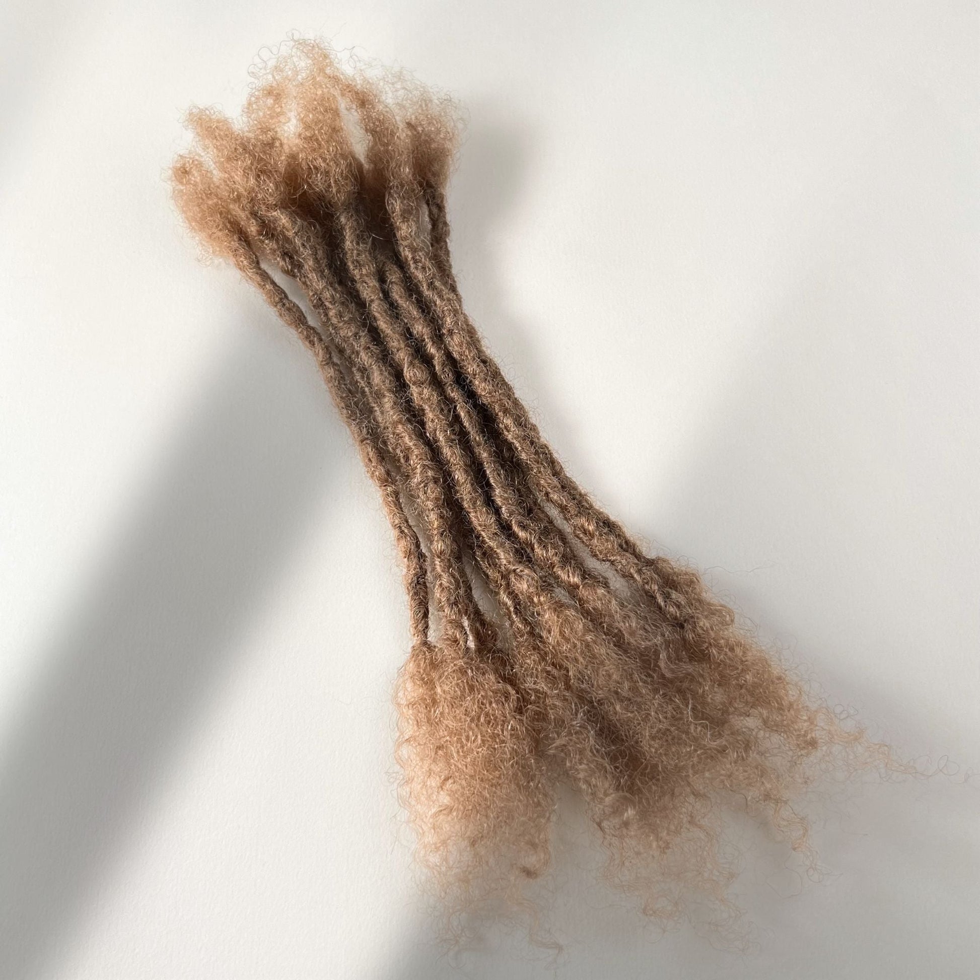 Dark Blonde kinky human hair open end loc extensions made using the interlocking method.