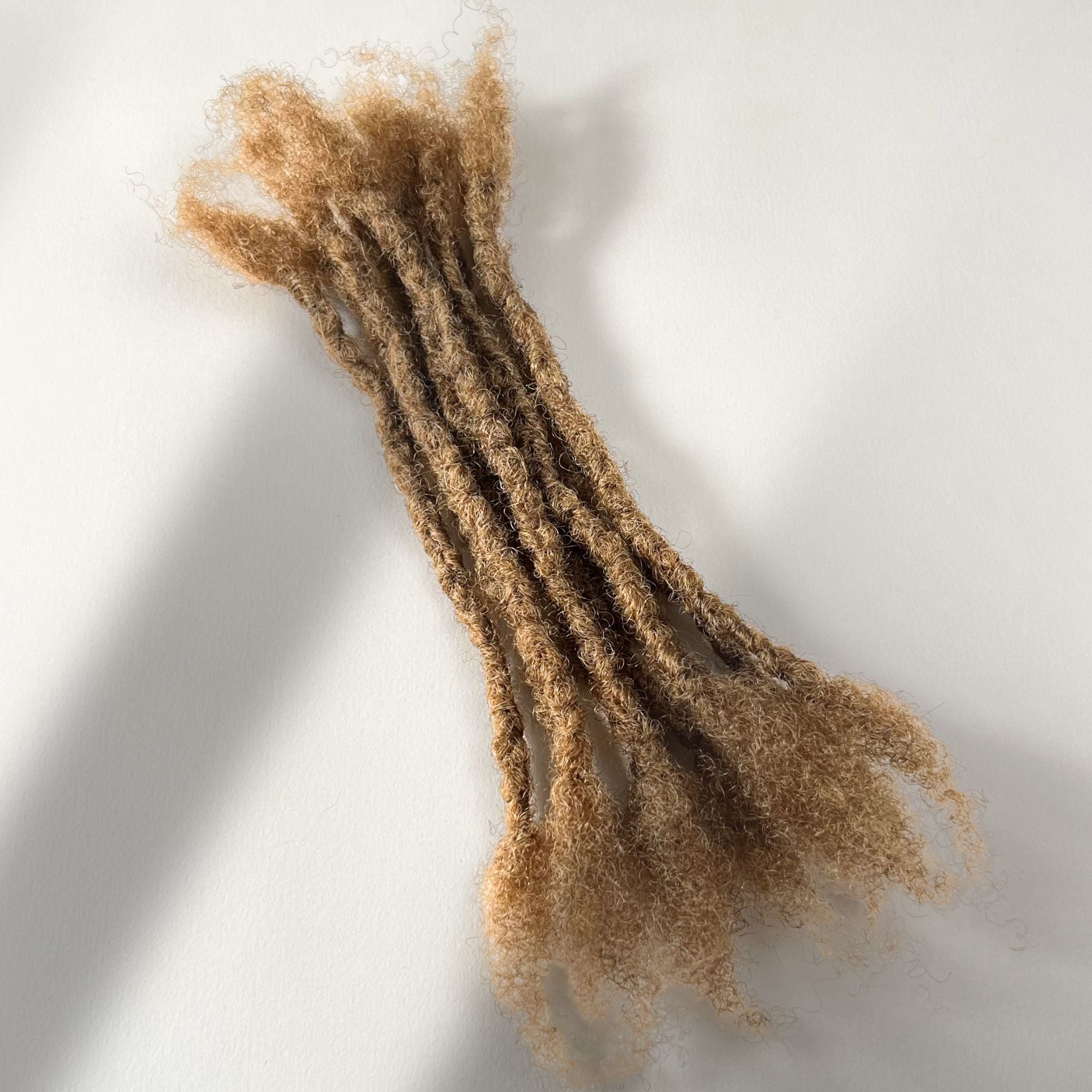 Honey Blonde kinky human hair open end loc extensions made using the interlocking method.