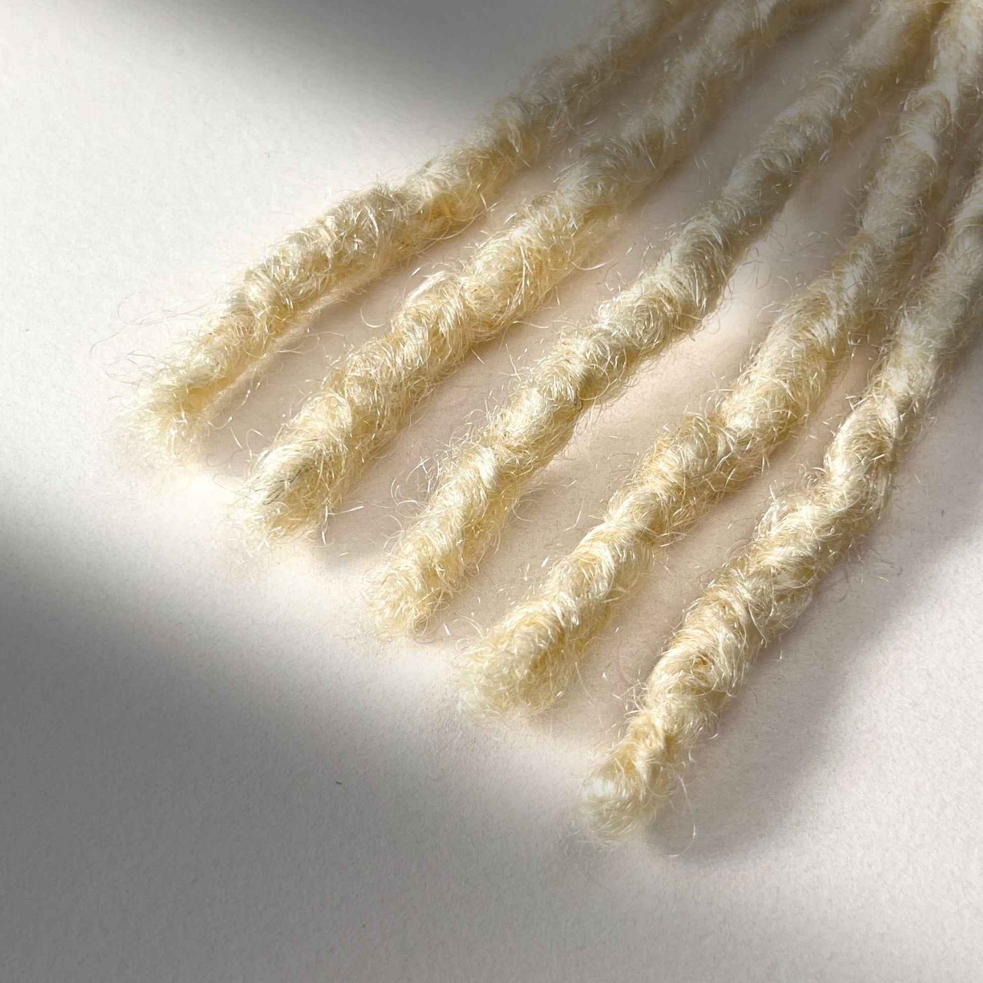 Tip detail of kinky loc extensions with blunt ends in Bleach Blonde.
