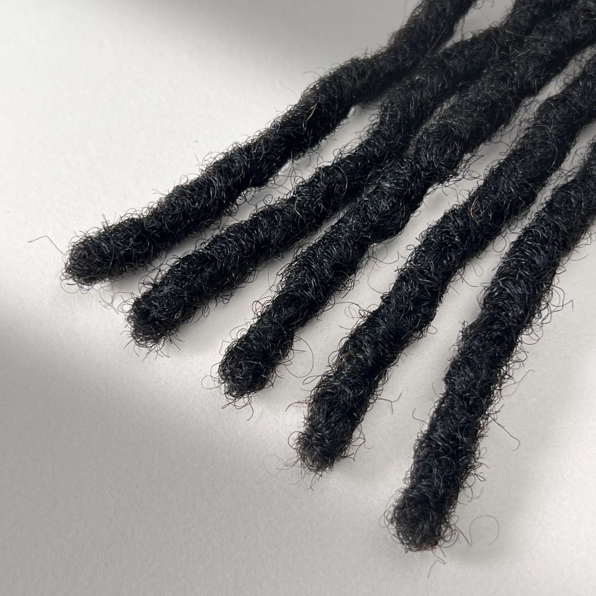 Tip detail of kinky loc extensions with blunt ends in Dark Brown.