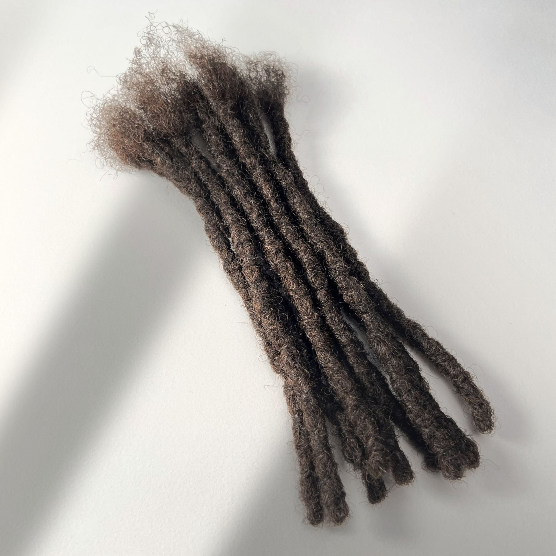 Full view of kinky loc extensions with blunt ends in Medium Brown, made using the interlocking method.