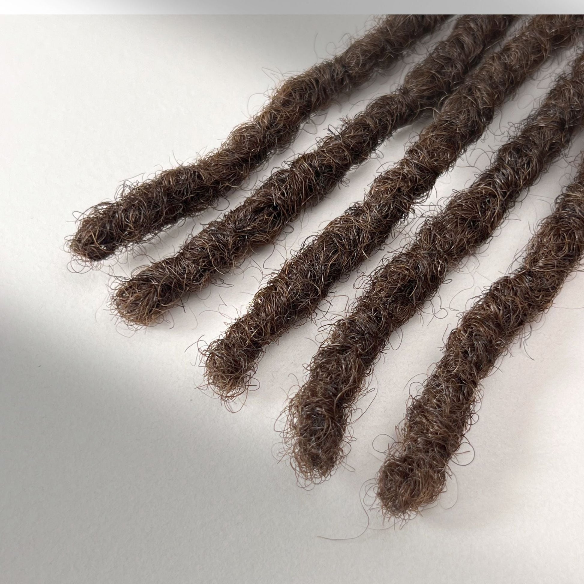 Tip detail of kinky loc extensions with blunt ends in Medium Brown.