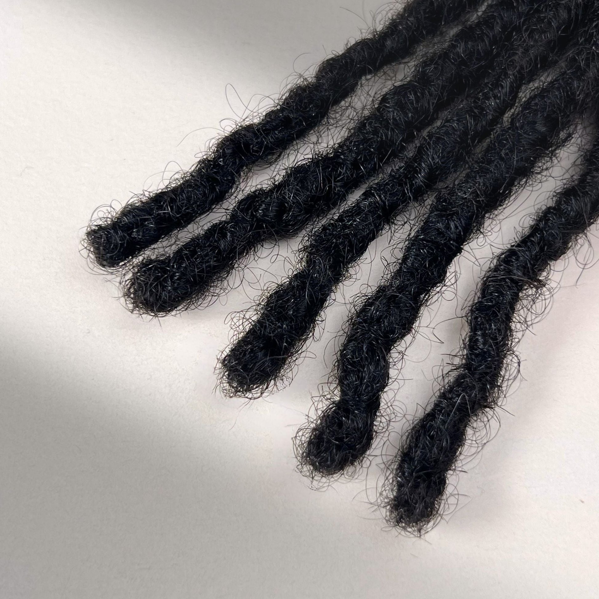 Tip detail of kinky loc extensions with blunt ends in Natural Black.