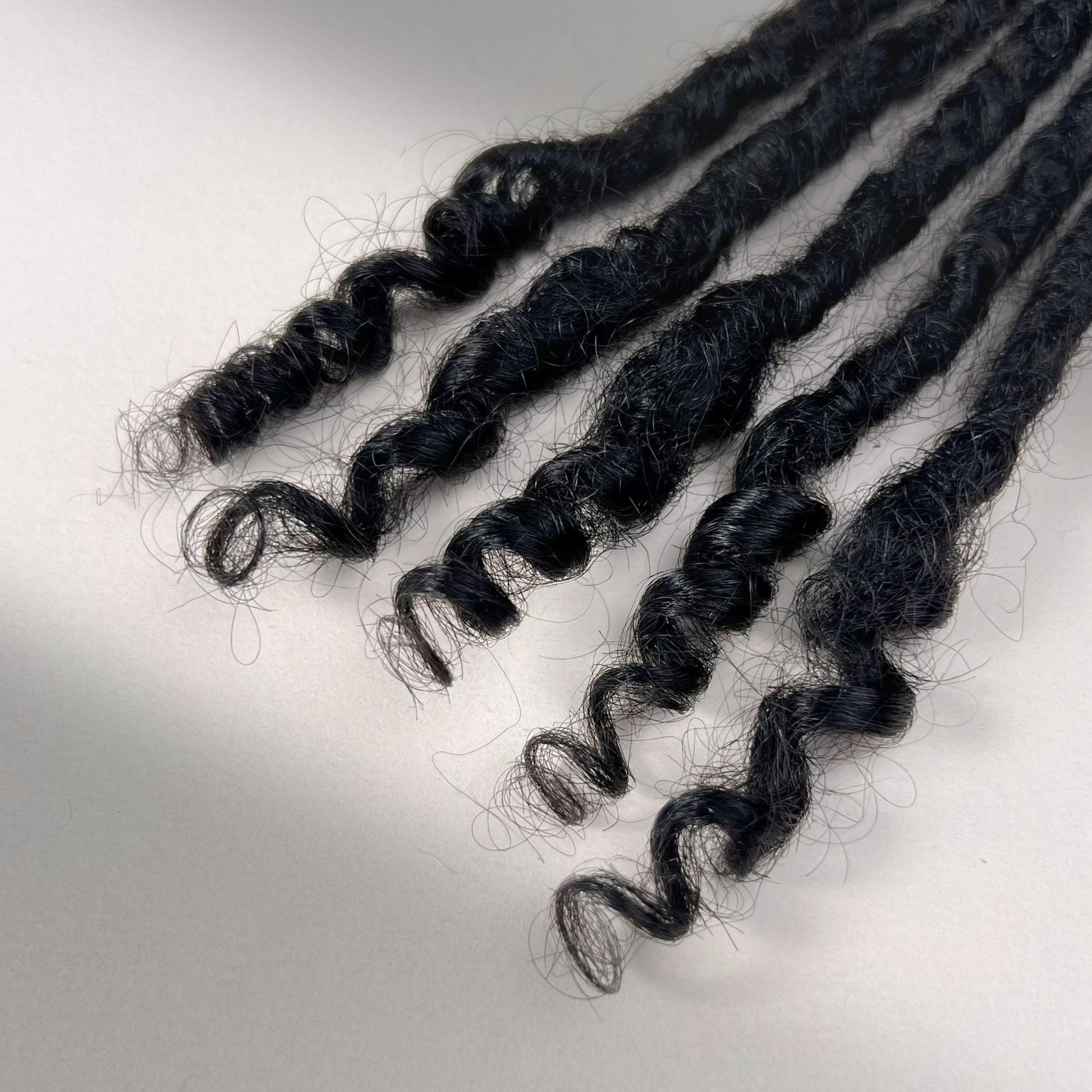 Tip detail of kinky loc extensions with curly ends in Natural Black.