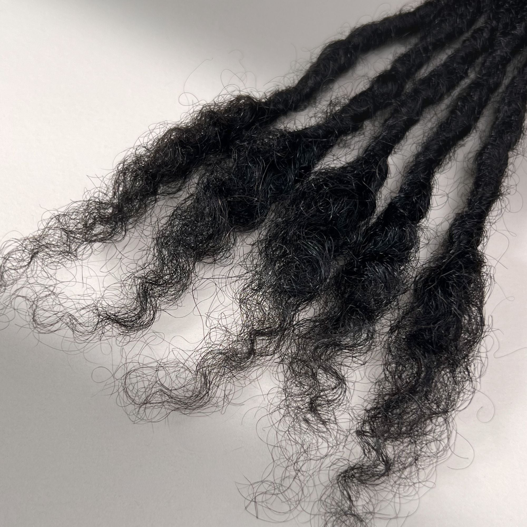 Tip detail of kinky loc extensions with open ends in Natural Black.