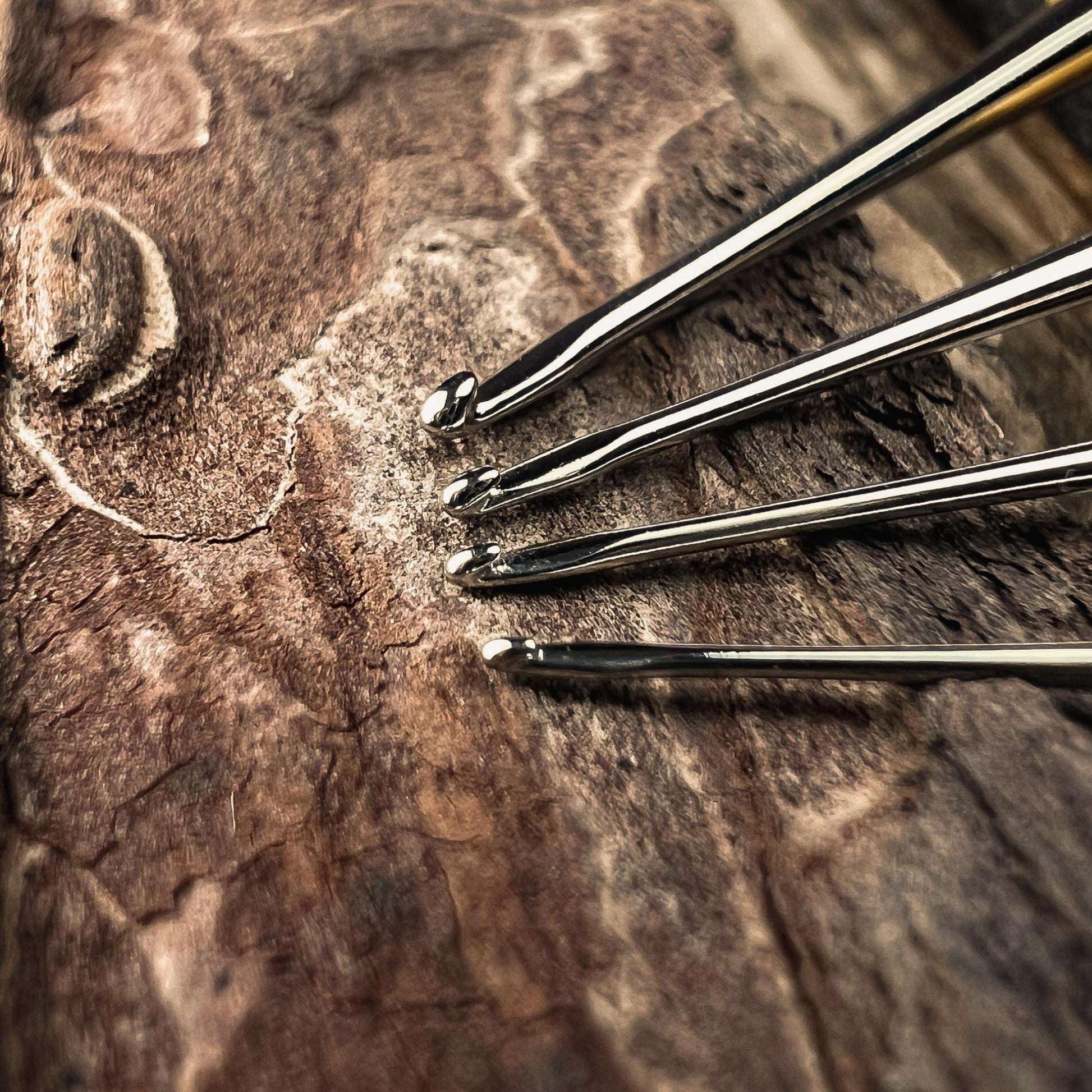 Size comparison of fine micro crochet hooks for Locs and Dreadlocks showing different hook sizes on a wooden background.