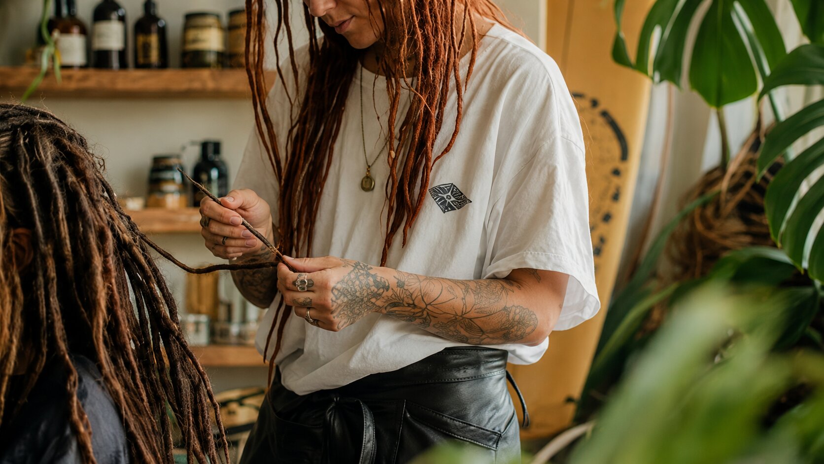 Loctician installing handmade human hair Locs on a client in a professional studio.