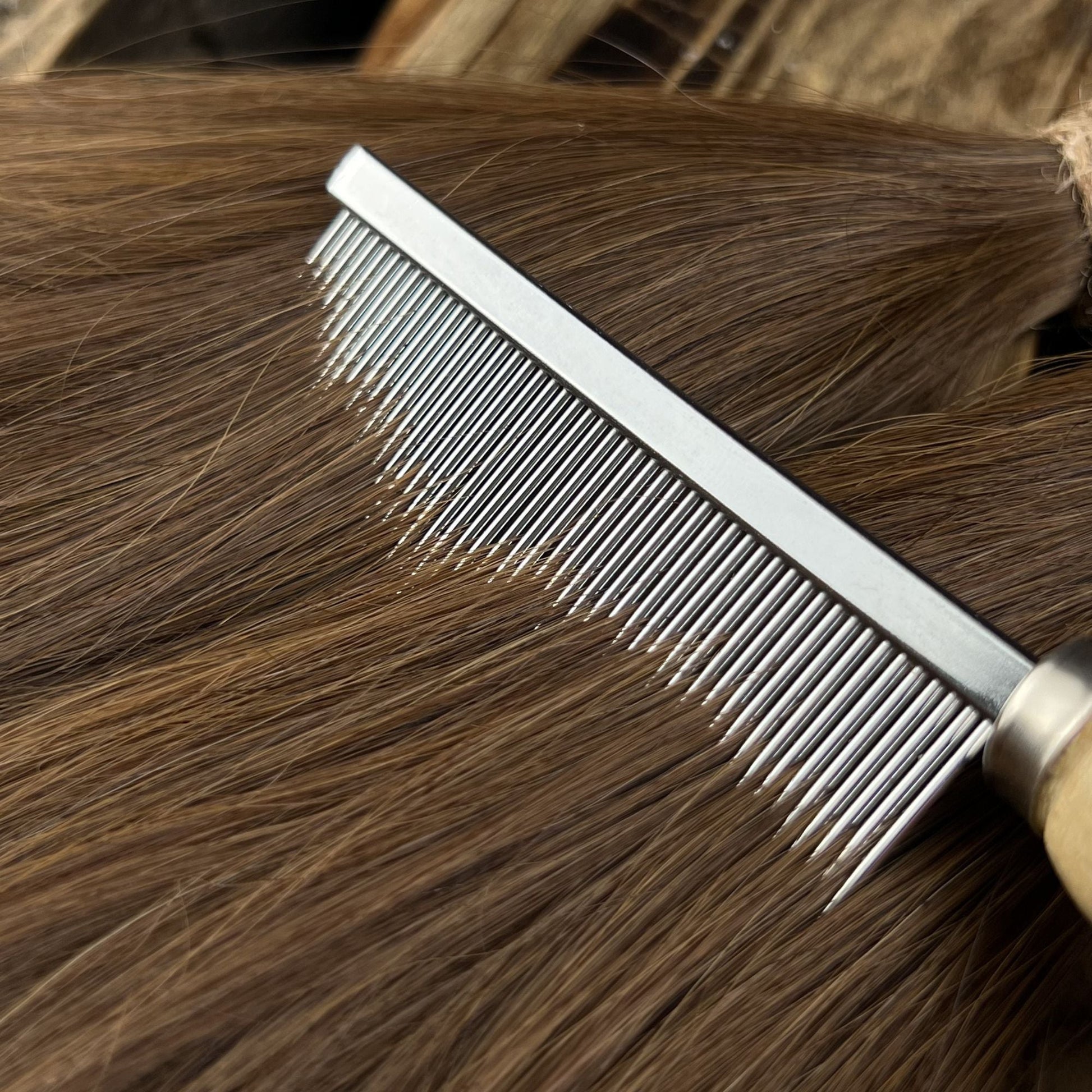 Close-up of straight brown human hair with a metal comb for preparing handmade Locs.
