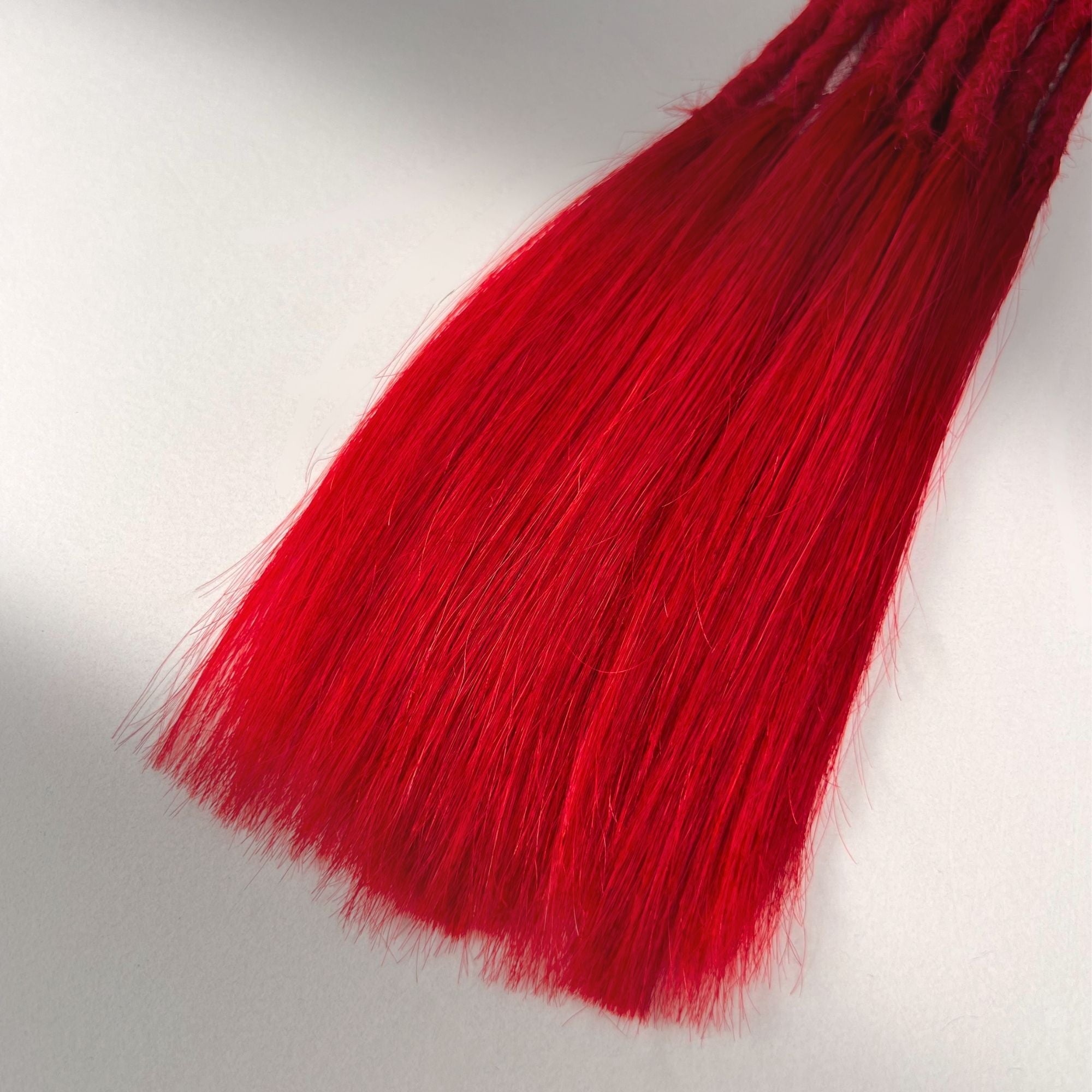 Tip detail of straight loc extensions with long loose ends in Flame Red.