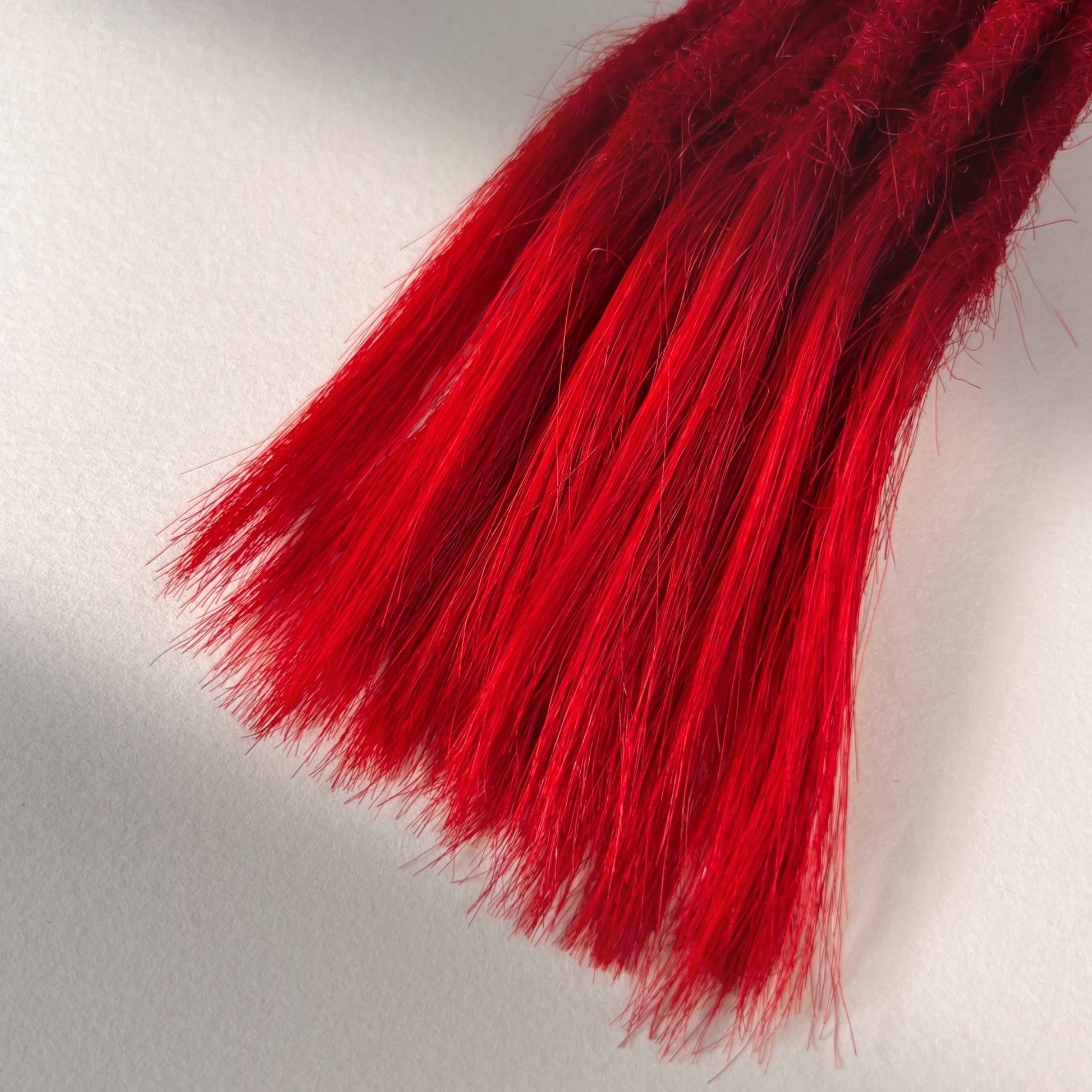 Tip detail of straight loc extensions with open ends in Flame Red.