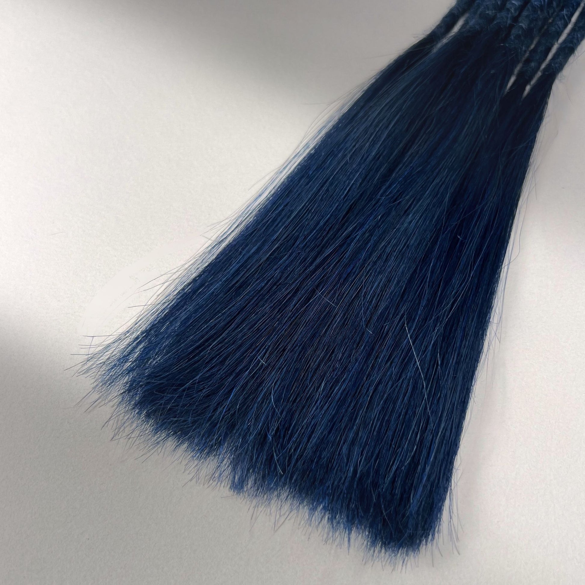 Tip detail of straight loc extensions with long loose ends in Midnight Blue.