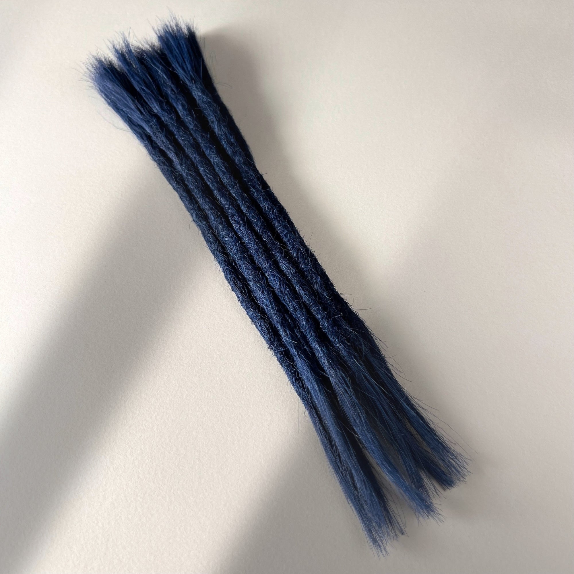 Full view of permanent straight loc extensions with open ends in Midnight Blue.