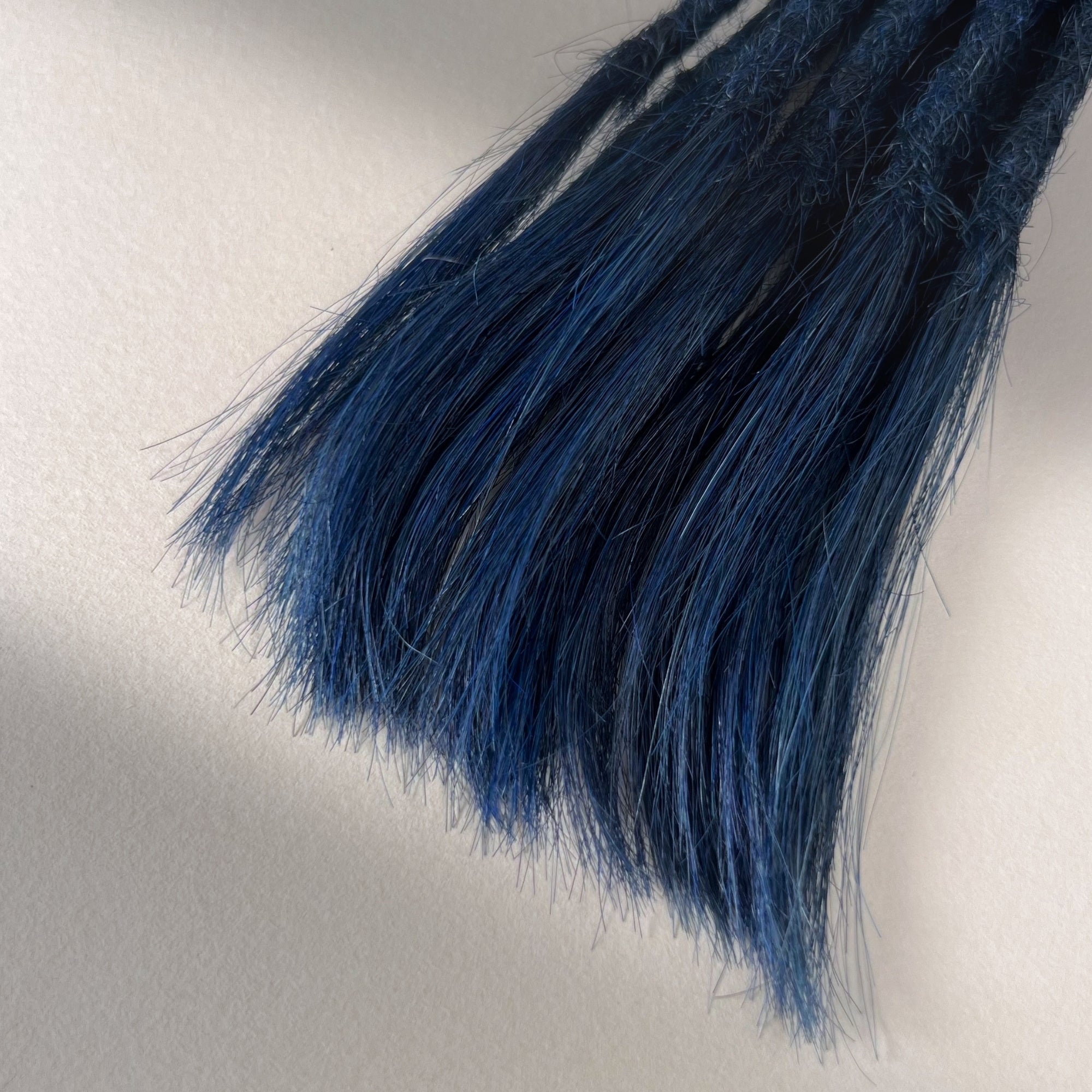 Tip detail of straight loc extensions with open ends in Midnight Blue.