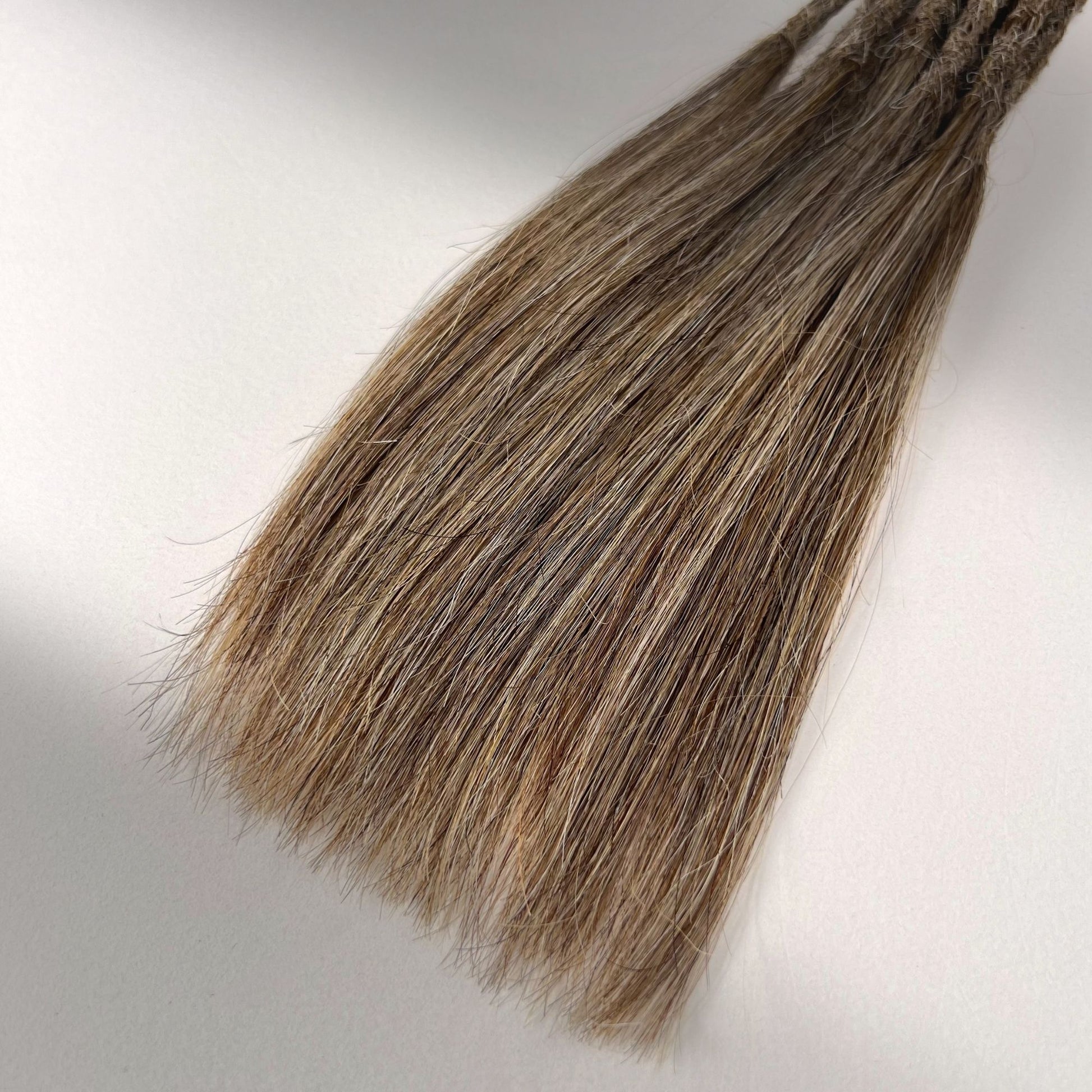 Tip detail of straight loc extensions with long loose ends in Sandy Blonde.