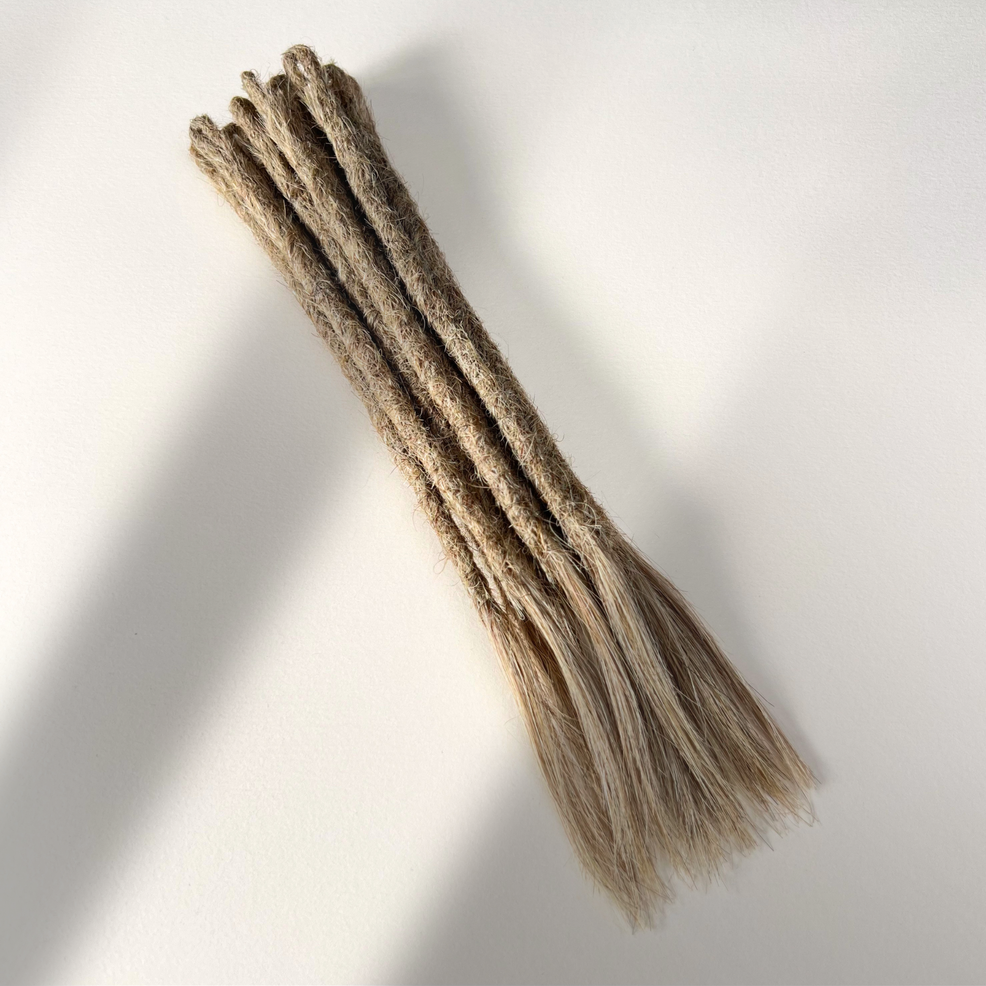 Full view of temporary single-ended straight loc extensions with open ends in Sandy Blonde.