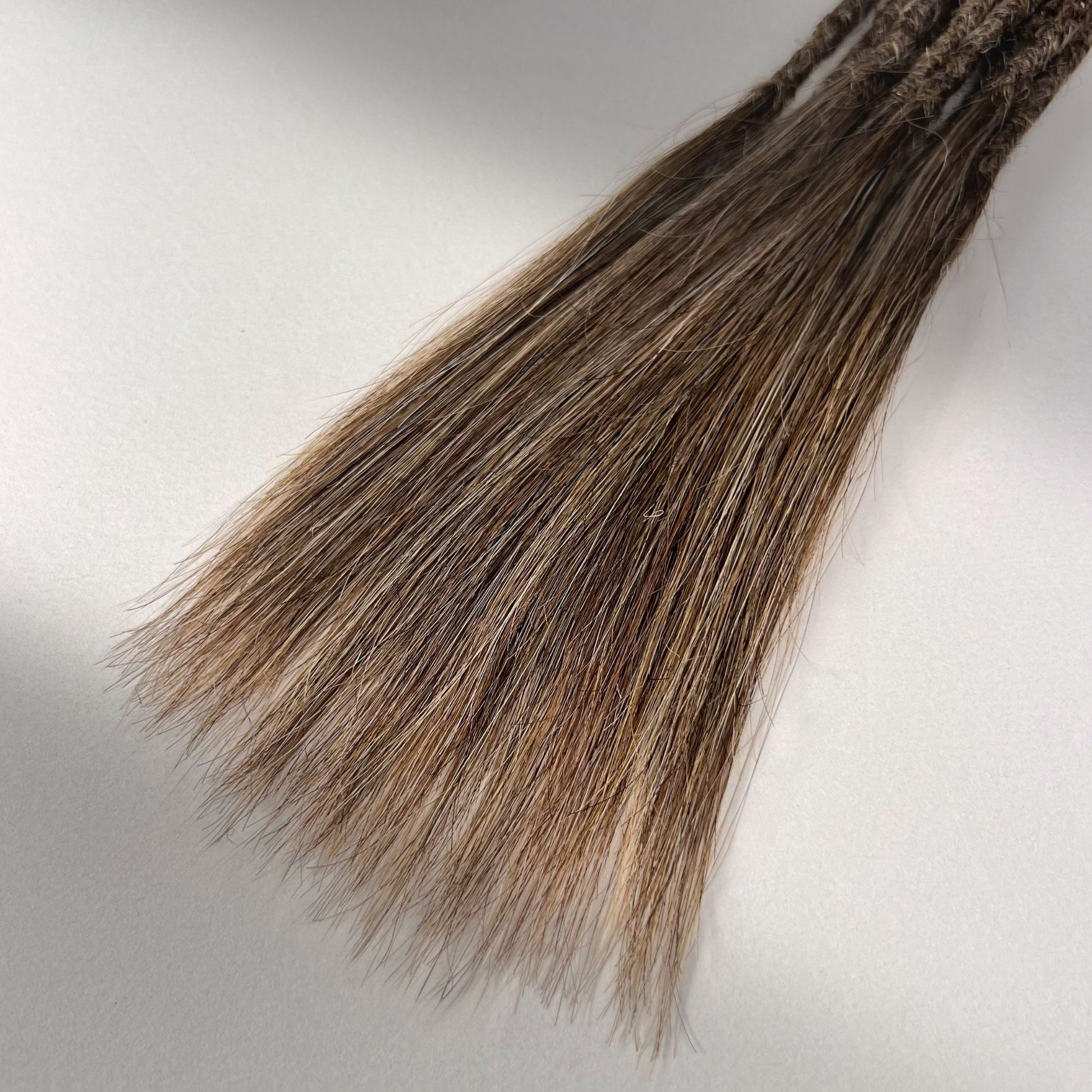 Tip detail of straight loc extensions with long loose ends in Light Beige Blonde.