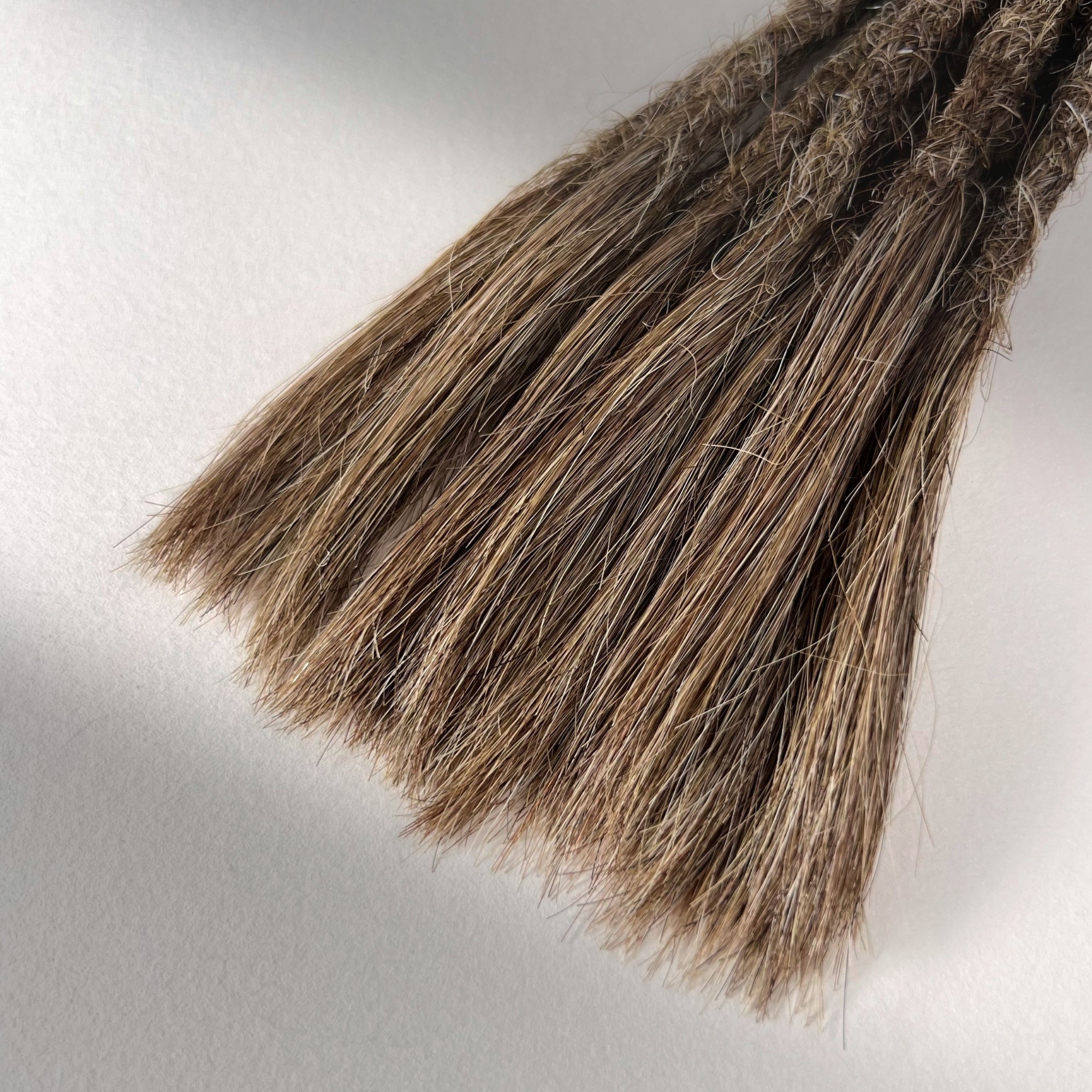Tip detail of straight loc extensions with open ends in Light Beige Blonde.