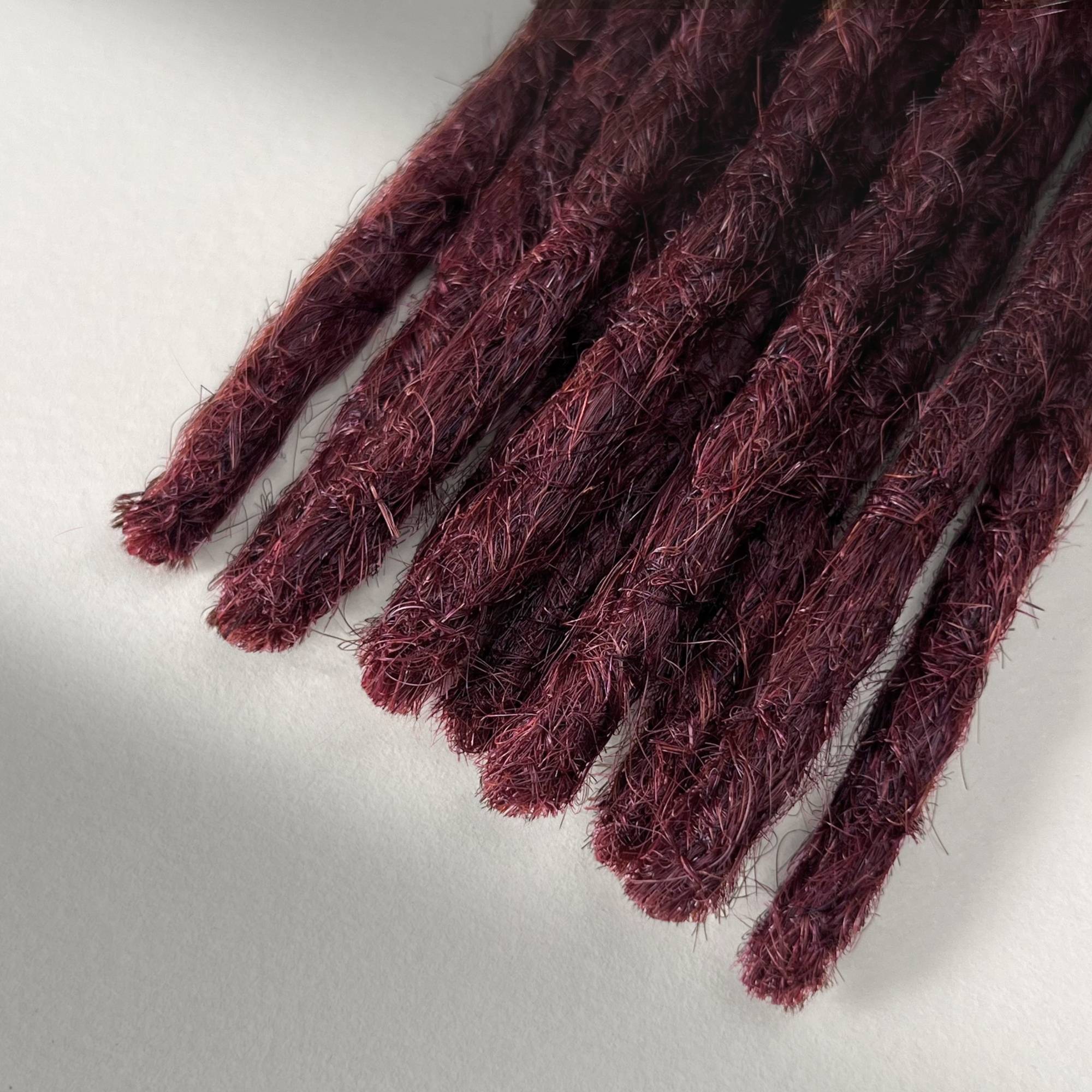 Tip detail of straight loc extensions with blunt ends in Rich Burgundy Red.
