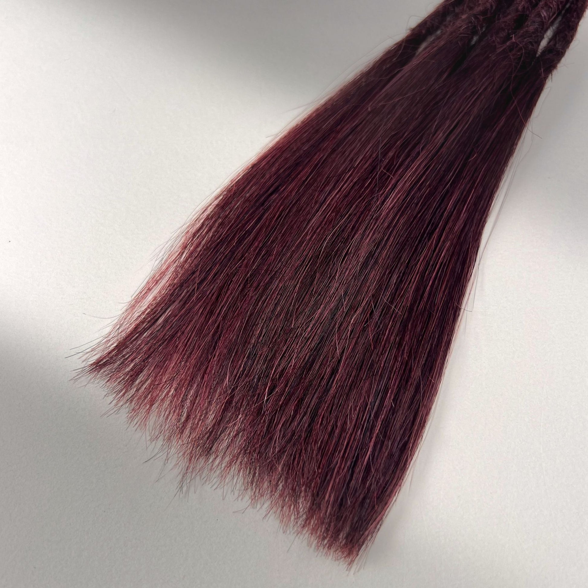Tip detail of straight loc extensions with long loose ends in Rich Burgundy Red.