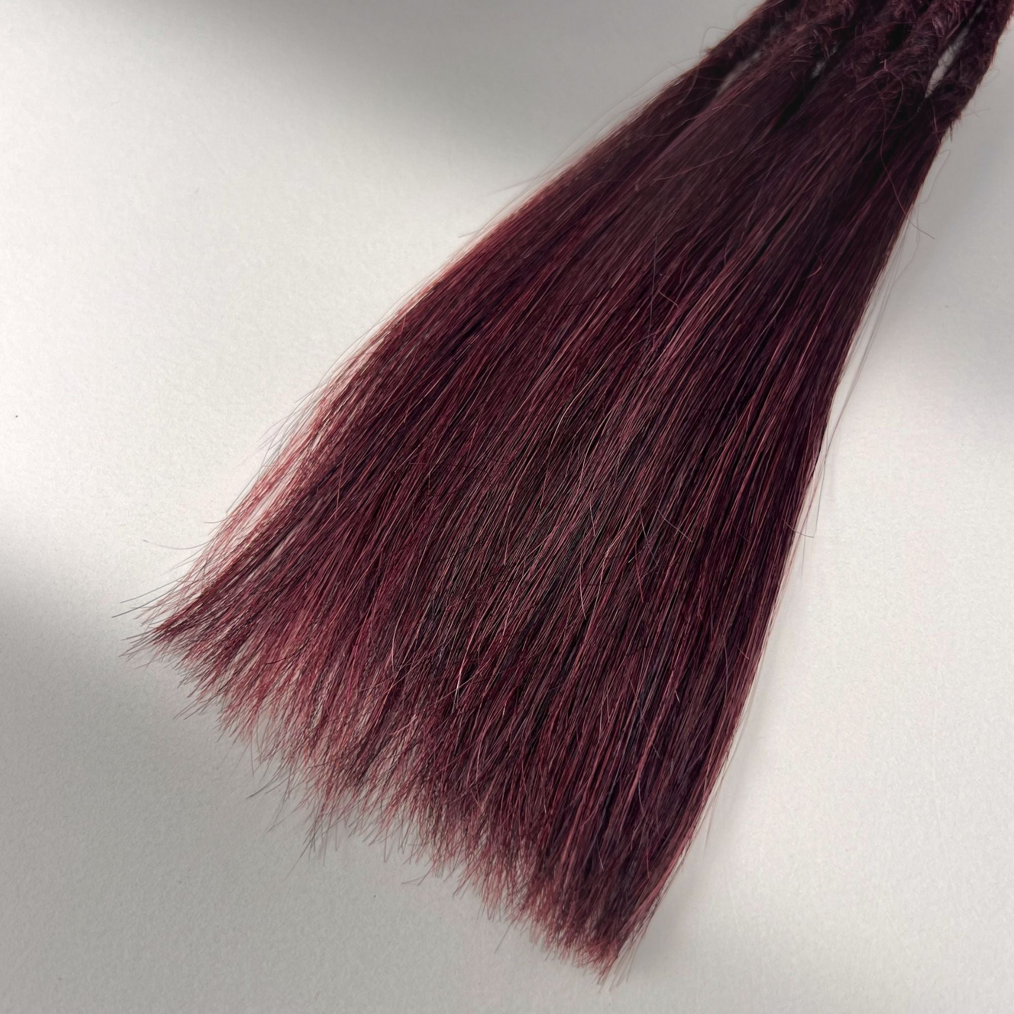 Tip detail of straight loc extensions with long loose ends in Rich Burgundy Red.