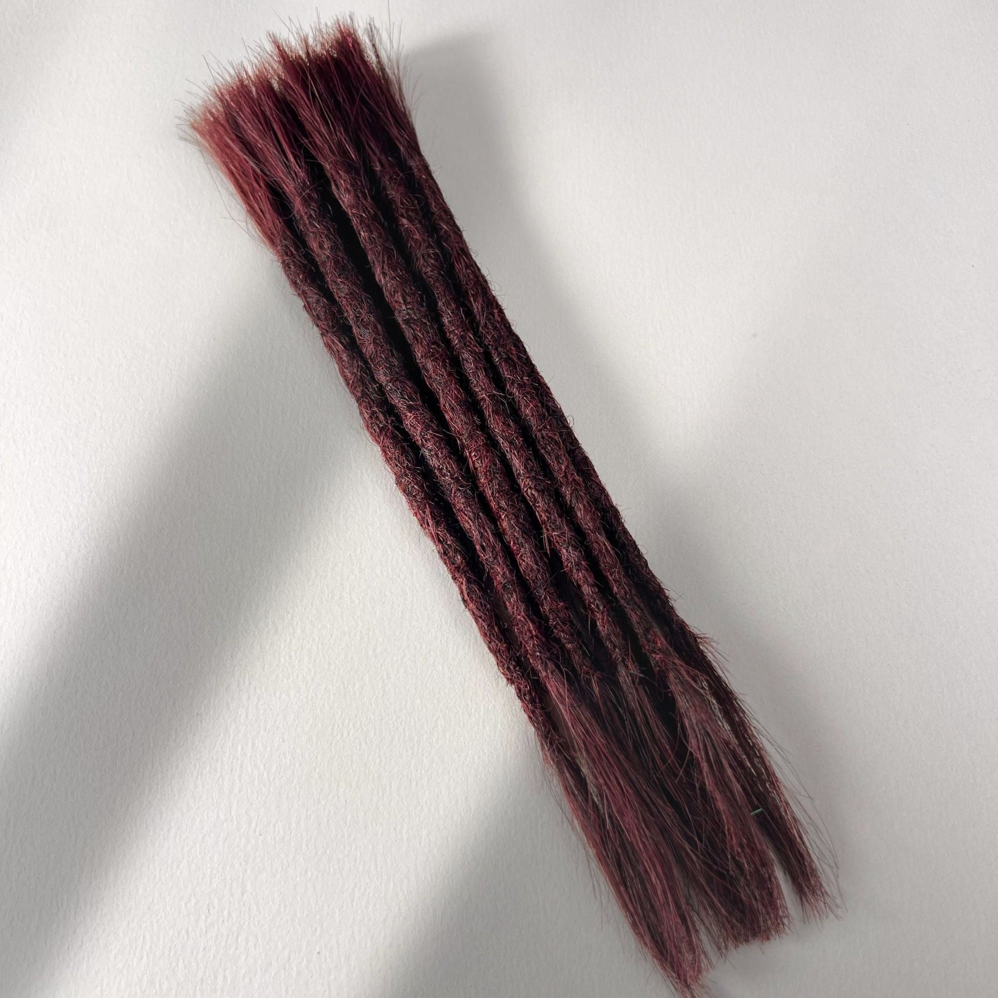 Full view of permanent straight loc extensions with open ends in Rich Burgundy Red.
