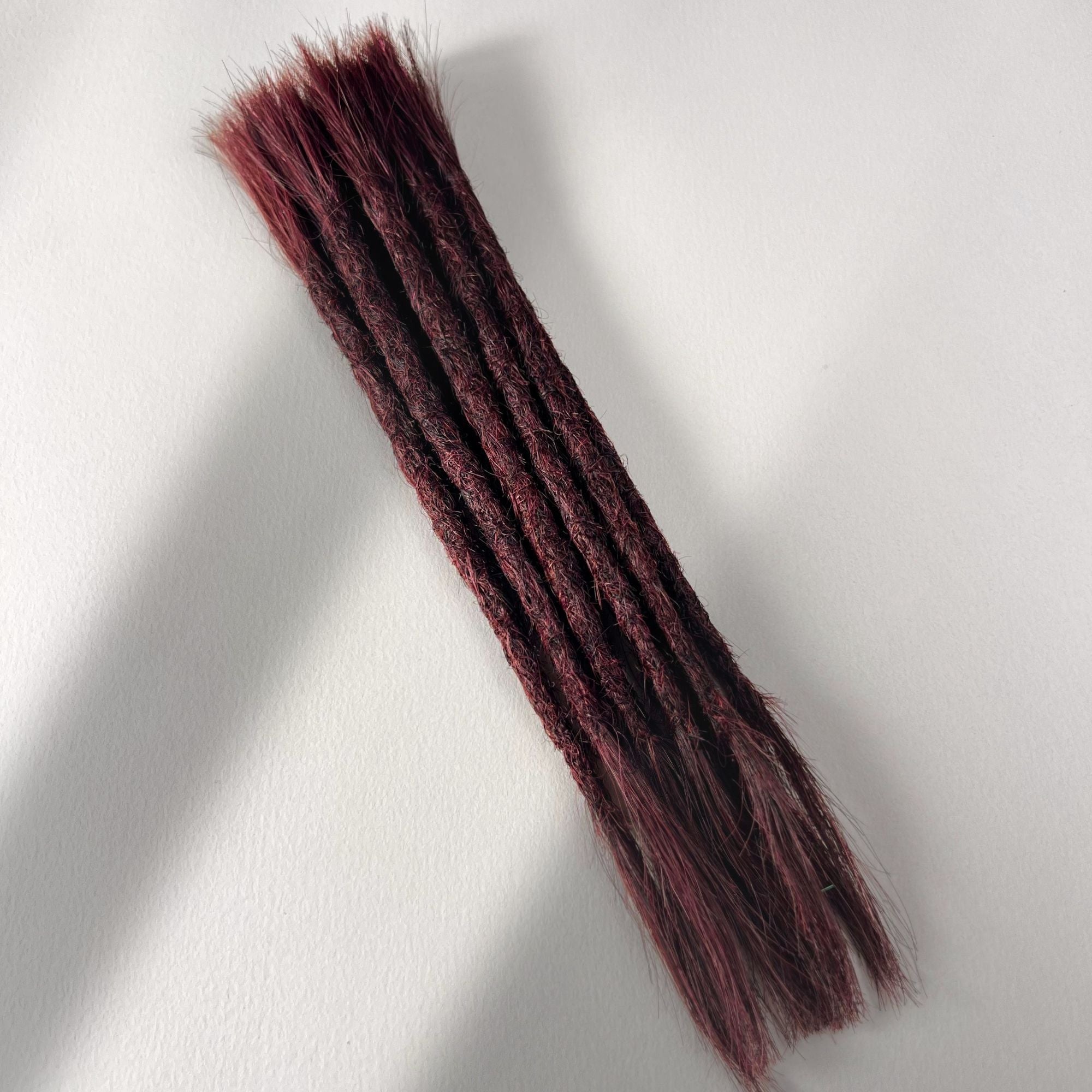 Full view of permanent straight loc extensions with open ends in Rich Burgundy Red.
