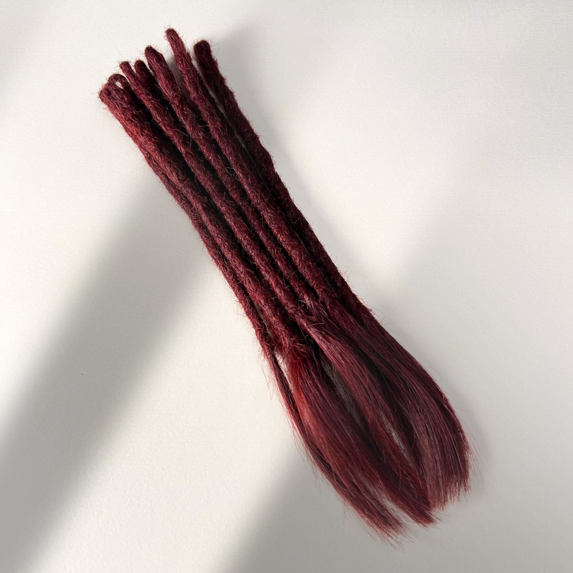 Full view of temporary single-ended straight loc extensions with open ends in Rich Burgundy Red.