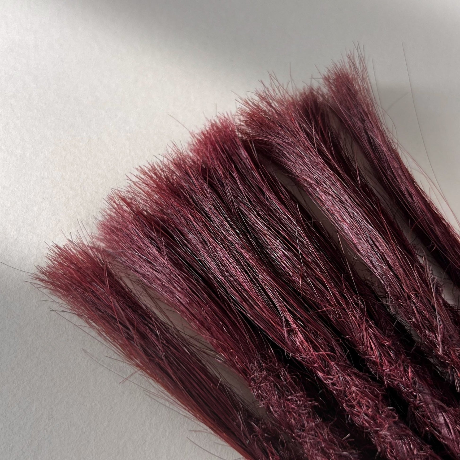 Connection point of permanent straight loc extensions in Rich Burgundy Red.