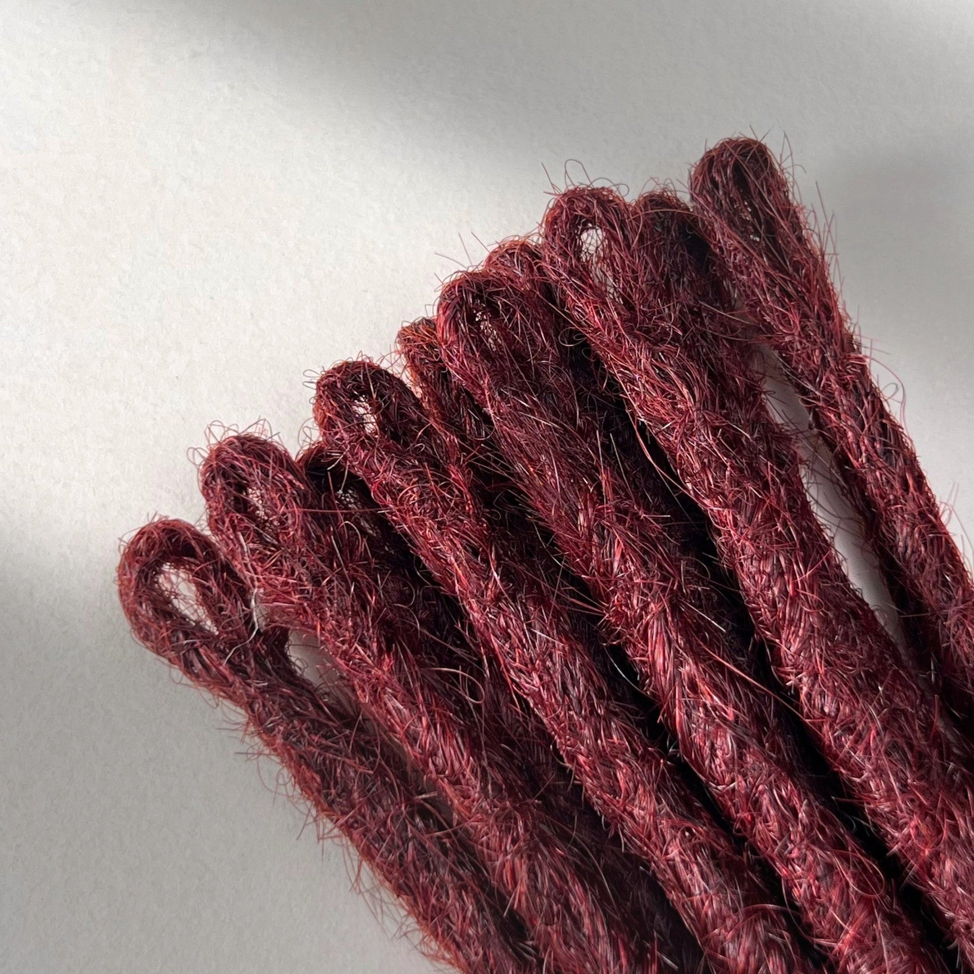Loop detail of temporary single-ended straight loc extensions in Rich Burgundy Red.