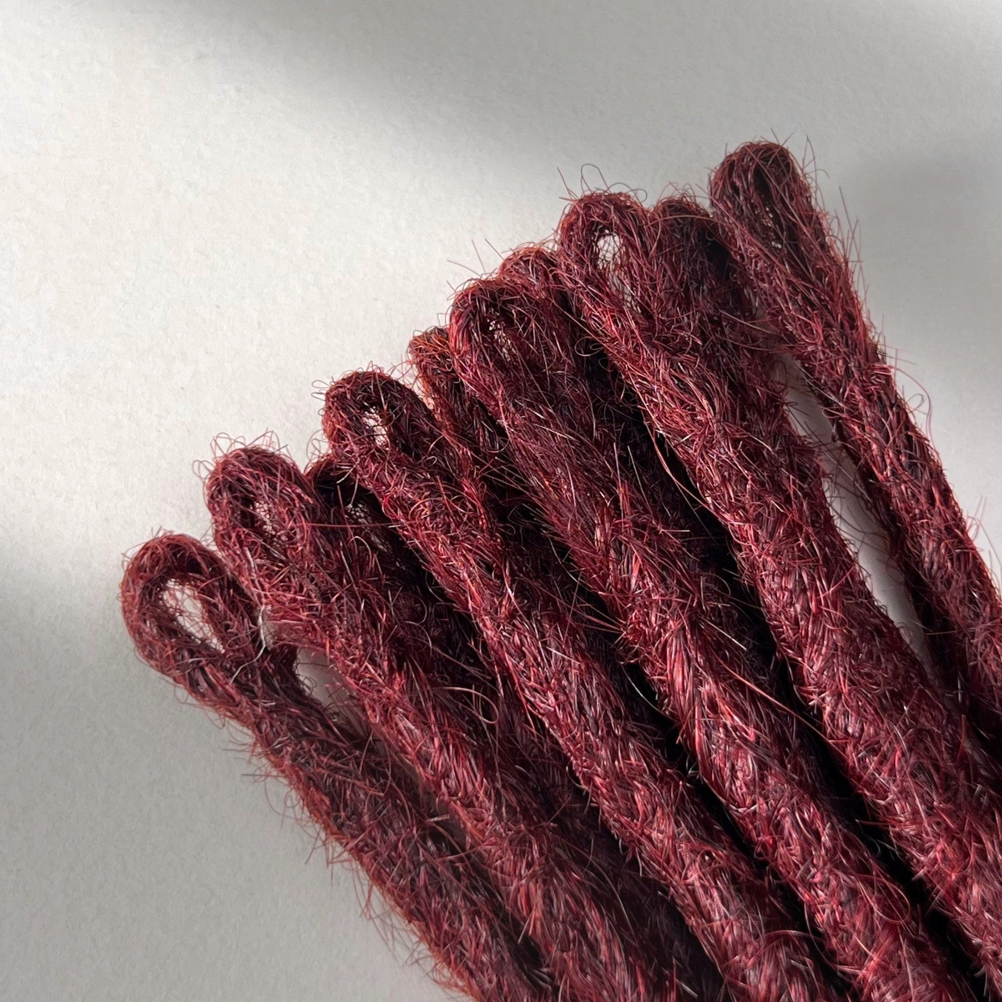 Loop detail of temporary single-ended straight loc extensions in Rich Burgundy Red.